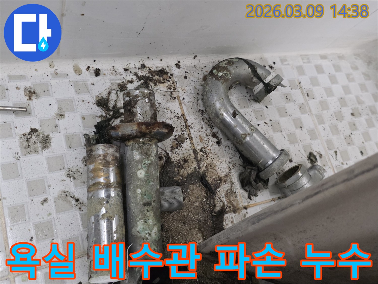 이 이미지는 심하게 부식되어 파손된 욕실 배수관과-그로 인해 발생한 오염된 바닥을 보여줍니다-누수 문제의 심각성을 나타냅니다