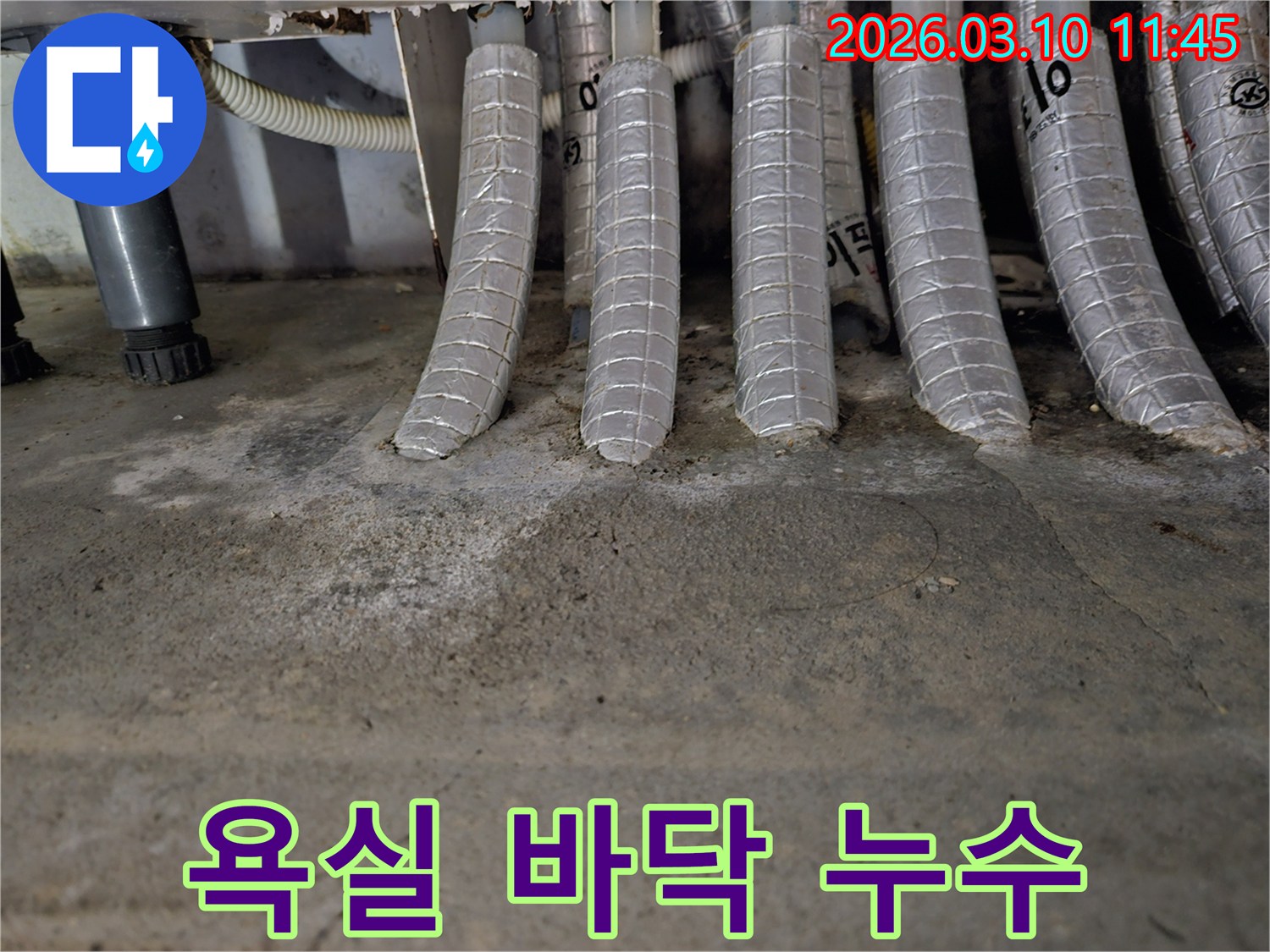 욕실-바닥의-콘크리트에-단열된-배관들이-연결된-지점에서-발견된-물-자국과-백화-현상을-촬영한-사진입니다