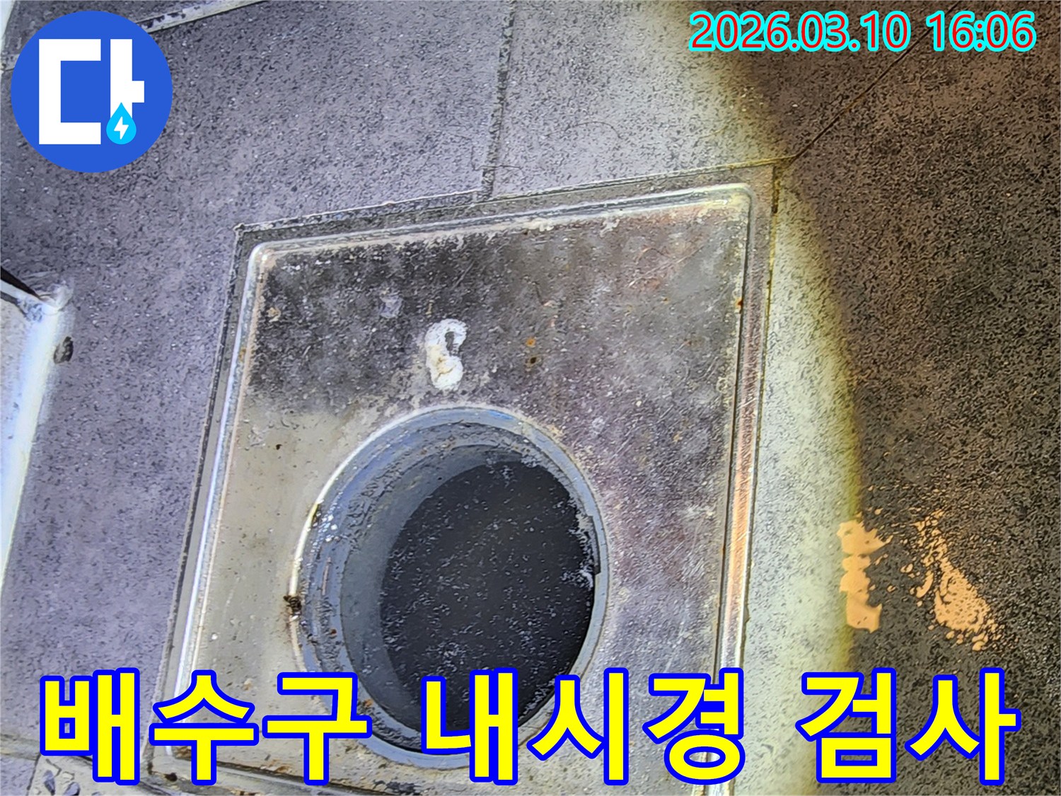 이 이미지는-서울 중구의 한 현장에서-배관 누수 원인을 찾기 위해-배수구 내부로-내시경 카메라를 삽입하여-정밀 검사를 진행하는-모습을 보여줍니다
