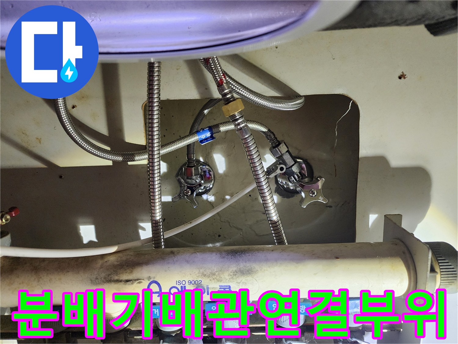싱크대 아래 보일러 분배기 밸브와 배관의 연결 상태를 보여주는 사진