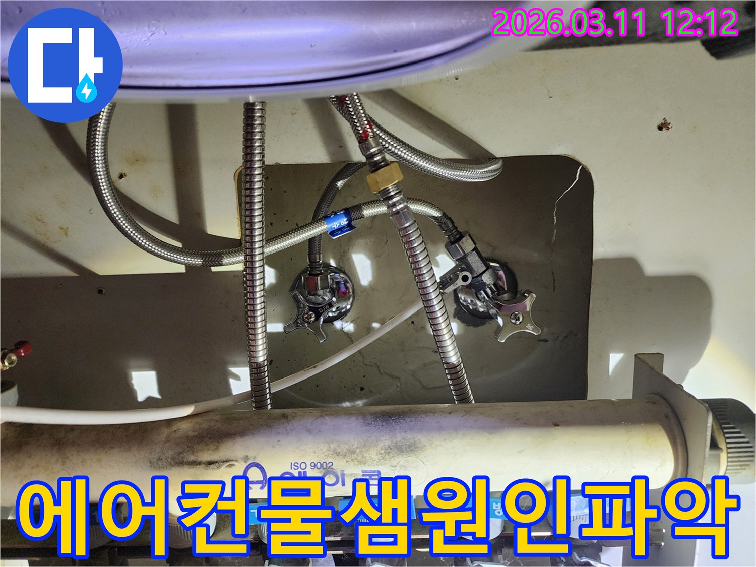 싱크대-아래-설치된-에어컨-배관-분배기와-수도-호스-밸브를-정밀하게-살펴보는-이미지