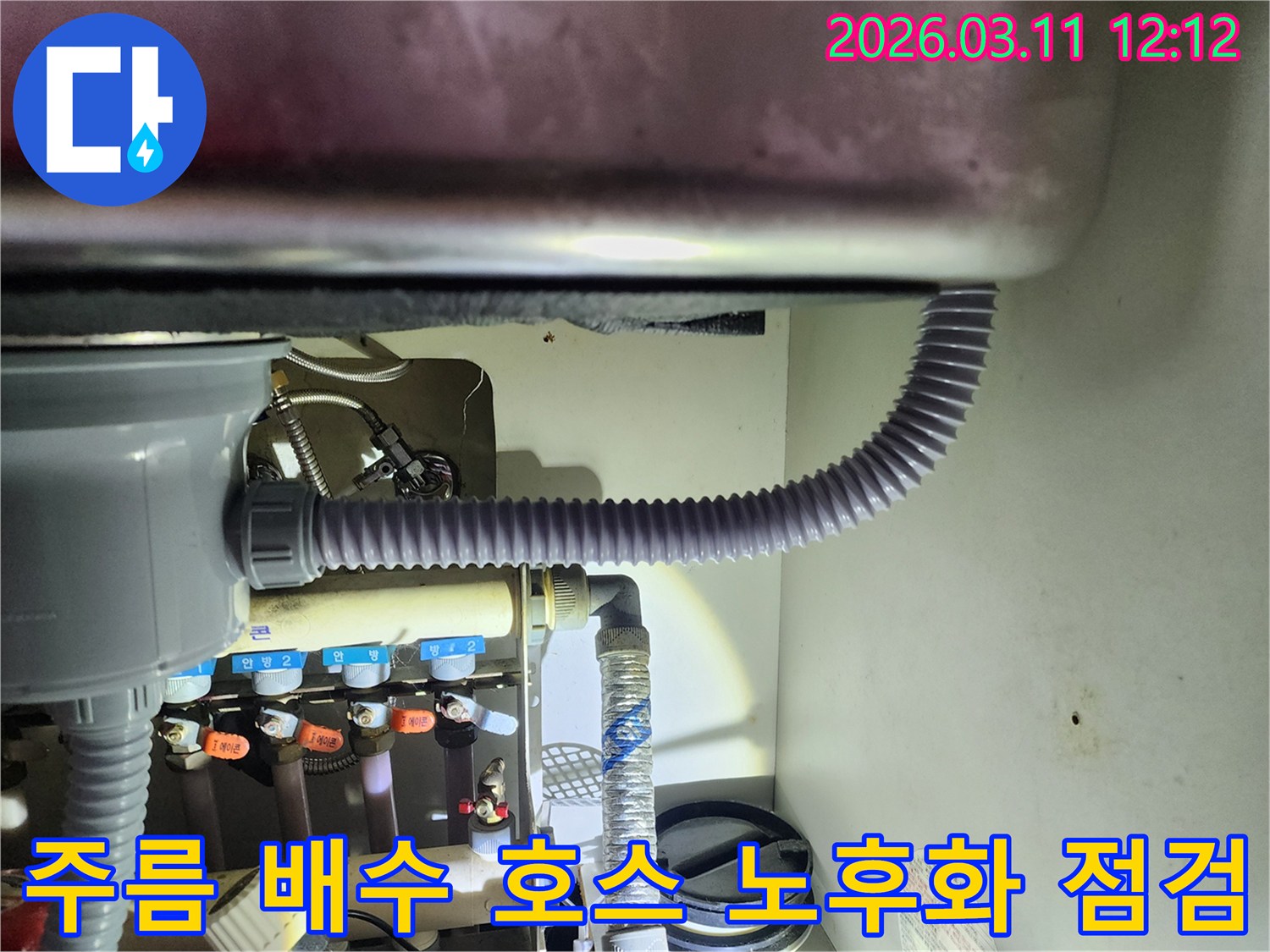 싱크대 하부의-주름진 배수 호스가-노후화되어-누수가 발생했는지-면밀히 점검하는 모습입니다