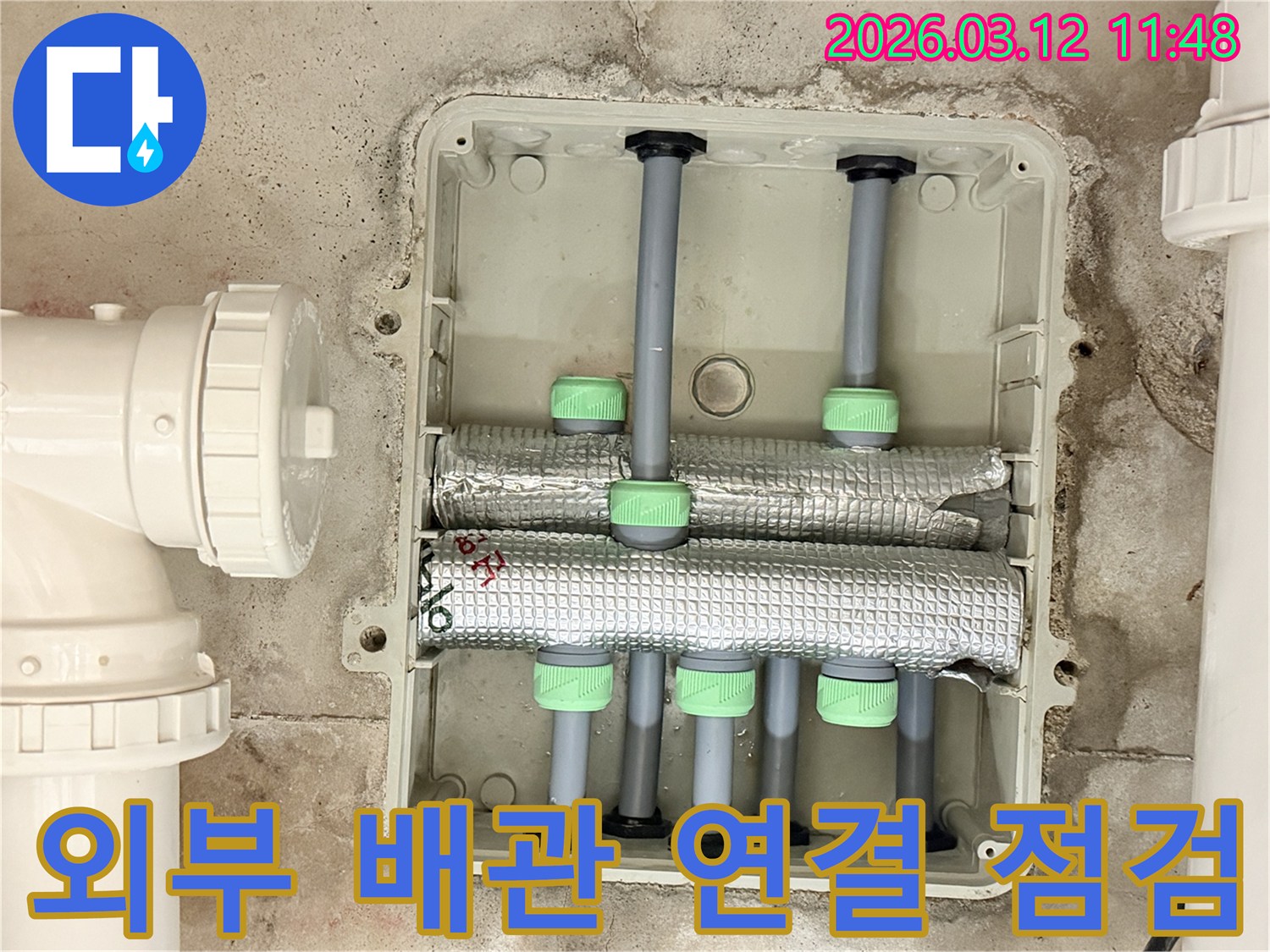 김포한강신도시 아파트의-배관 시스템에서-외부로 연결된 흰색 배관의-연결 부위를-전문가가 집중적으로 점검하는 모습