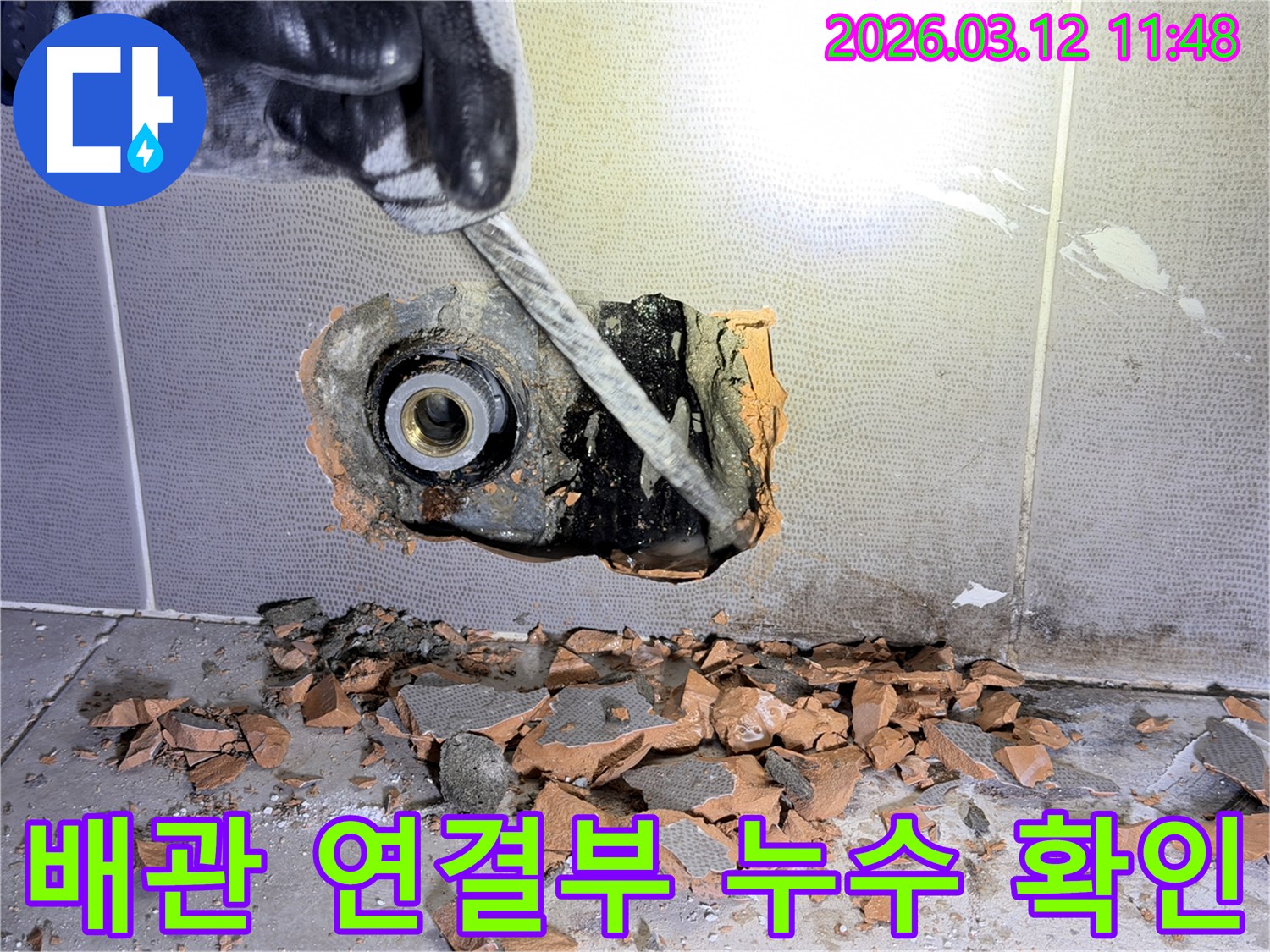 장갑 낀 손이-벽 속 배관 연결부의 누수 지점을-정밀하게 탐지하기 위해-해체하는 모습입니다