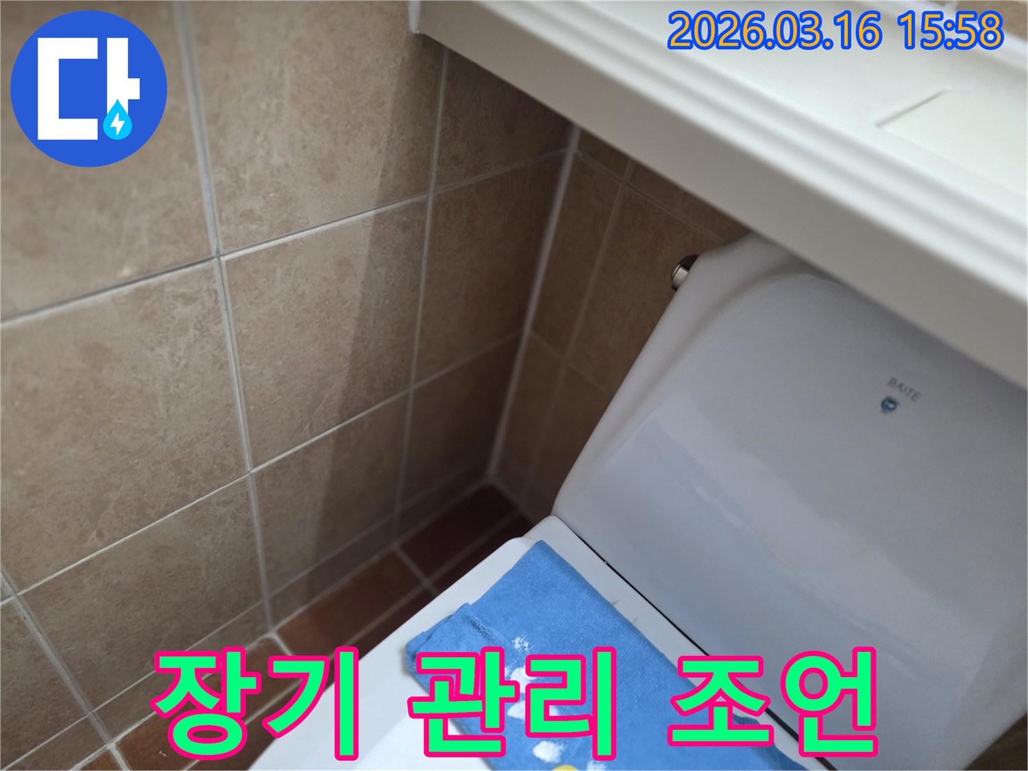 오산시 운암동의-한 욕실에서-변기 뒤편-벽면 타일의 젖음으로-누수 수리 후-장기적인 관리를 위한-조언을 제공하는-현장을 보여주는-사진입니다.