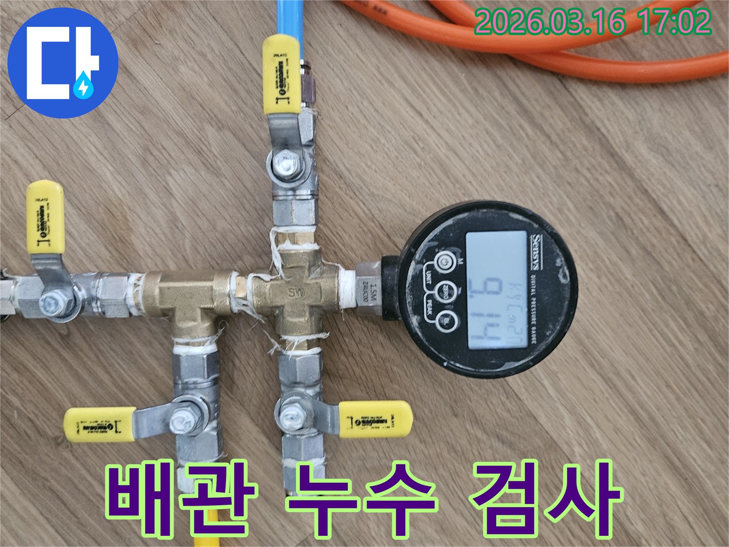 누수 탐지 전문가가-배관의 건전성을 확인하고자-압력 테스트 장치를 설치하고-압력계의 수치를-주의 깊게 관찰하는-장면입니다.