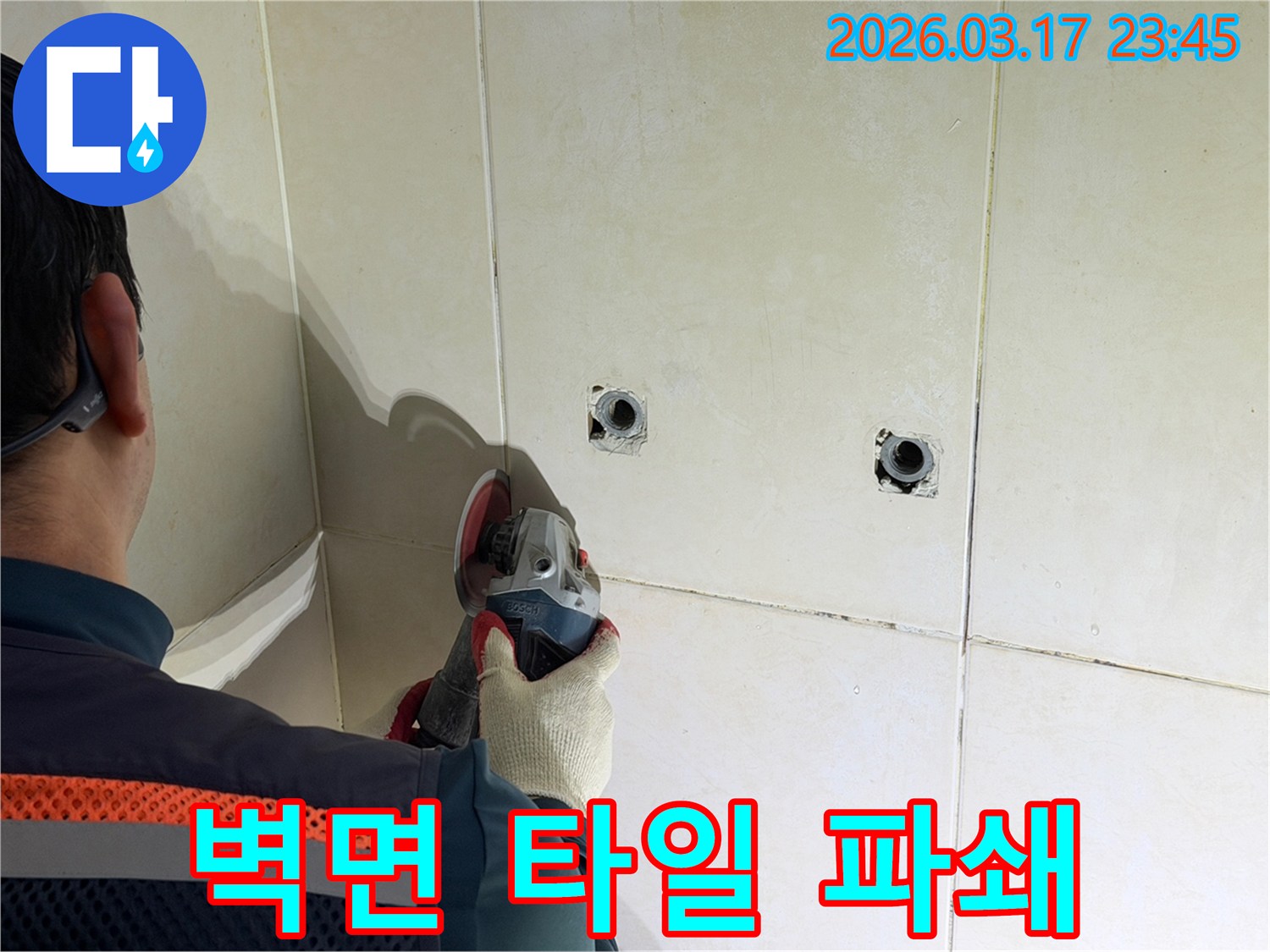 누수된 배관을-노출시키기 위해-전문가가-벽면 타일을-그라인더로-조심스럽게-파쇄하고-있습니다