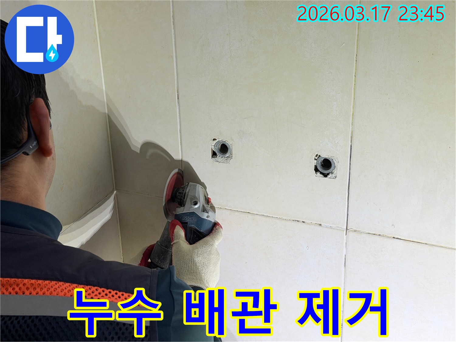 누수된 배관을-노출시키기 위해-전문가가-타일 벽면을-그라인더로-조심스럽게-제거하고-있습니다