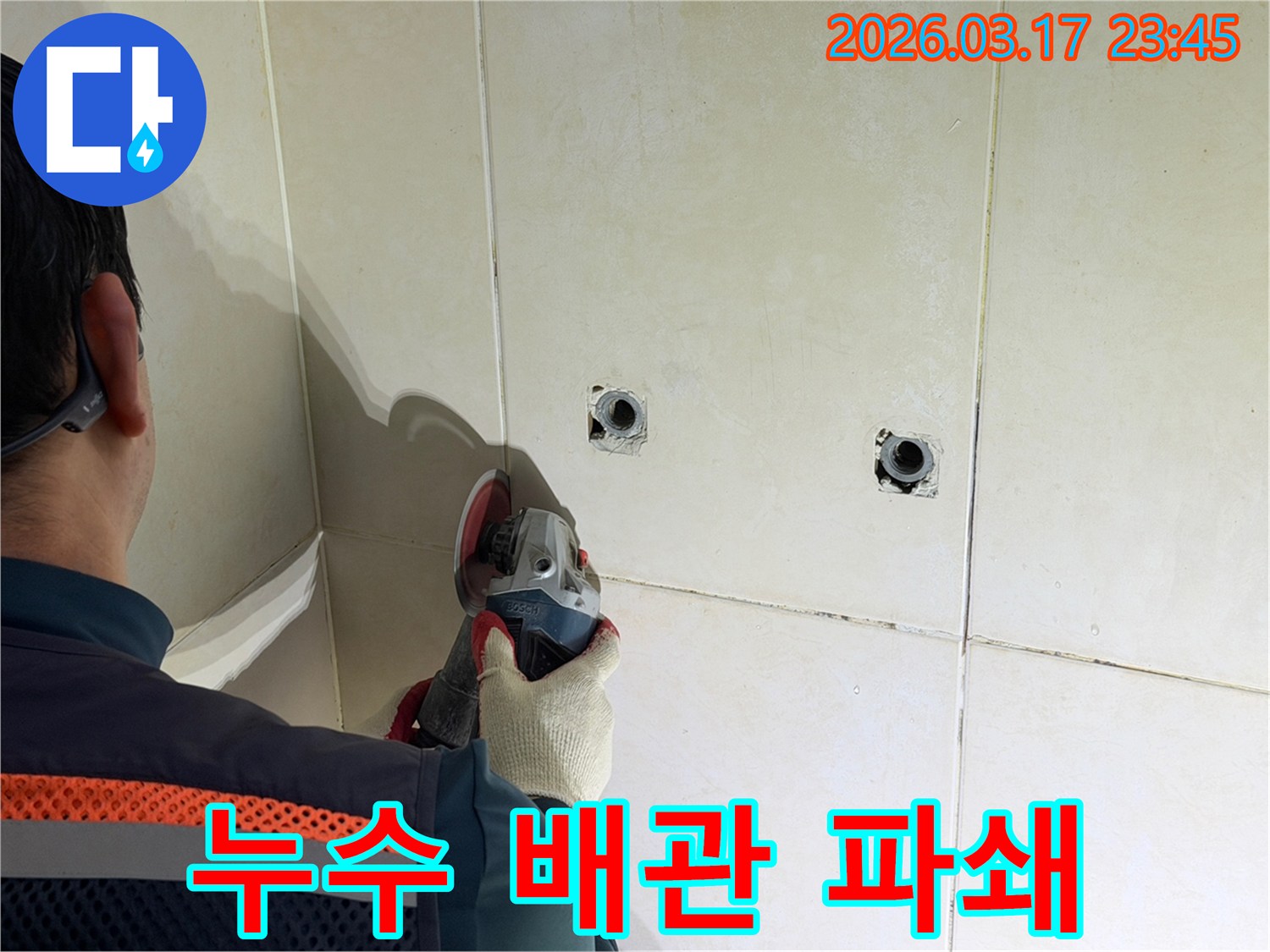 누수된 배관을-노출시키기 위해-전문가가-타일 벽면을-그라인더로-조심스럽게-파쇄하고-있습니다