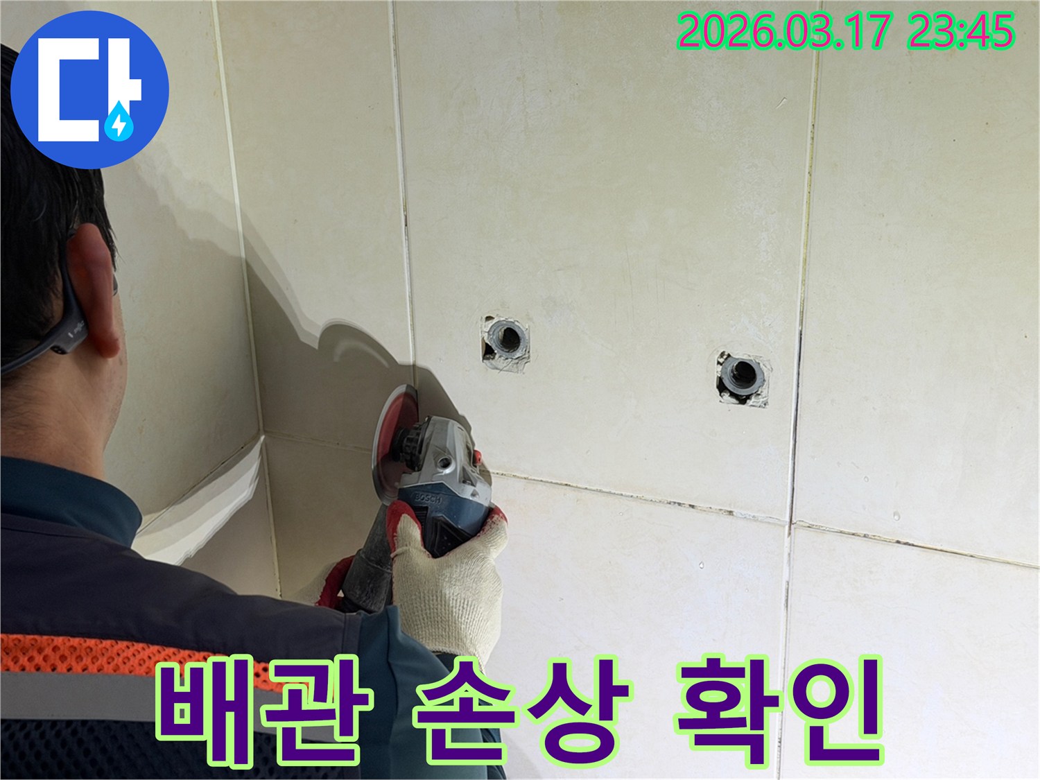누수된 배관의-손상 부위를-확인하기 위해-전문가가-타일 벽면을-그라인더로-파쇄하는-작업을-진행하고-있습니다