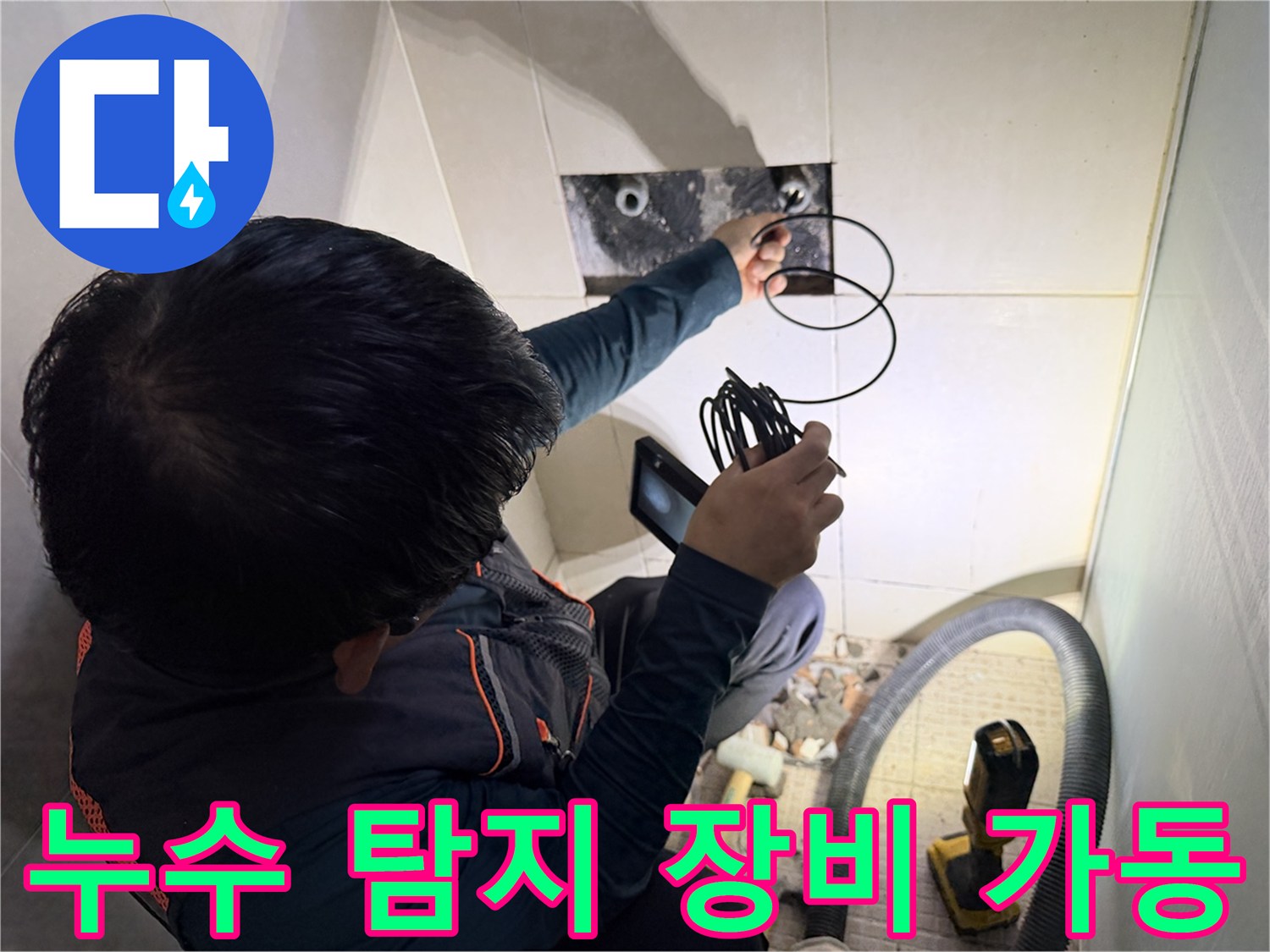 벽면 타일 사이로 연결된 배관의 누수 여부를 확인하기 위해 검사 장비를 운용하고 있습니다.