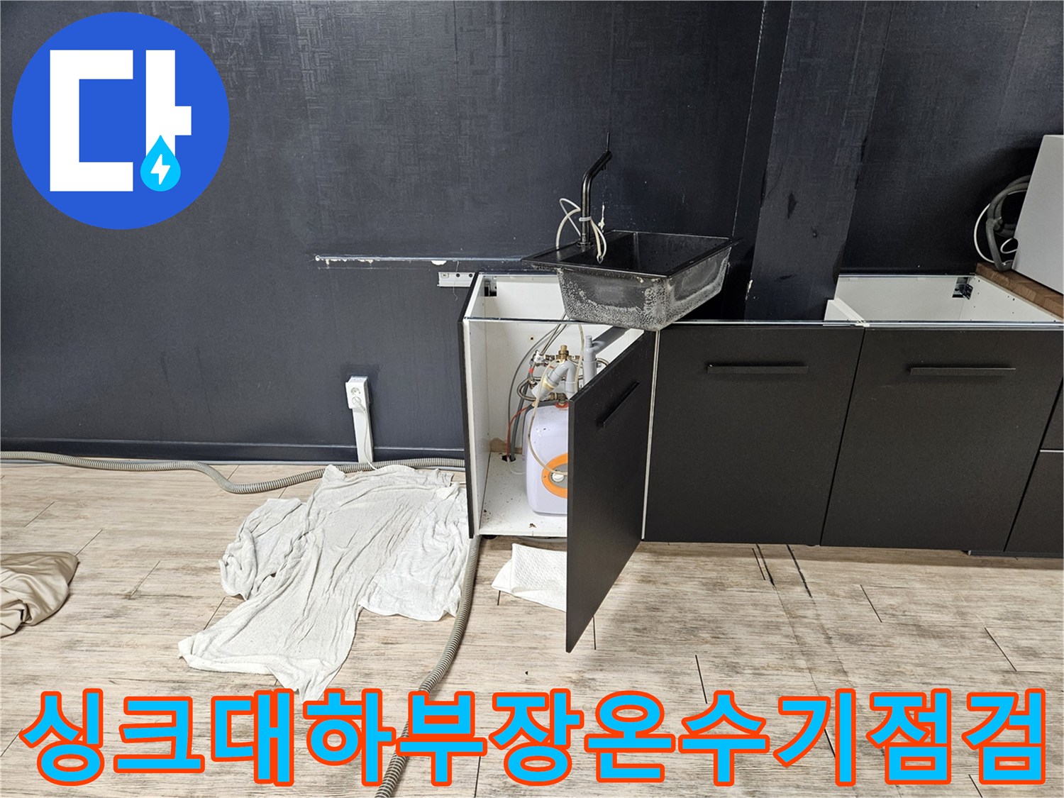 싱크대-하부장에-설치된-소형-전기-온수기와-배관-상태를-확인하는-모습