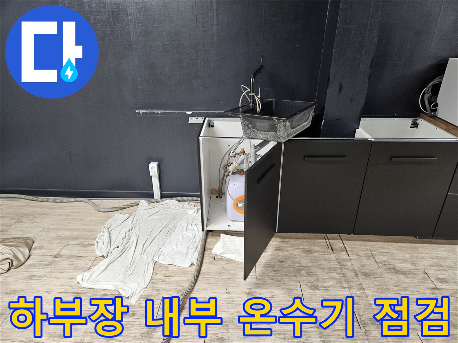 열린 싱크대 하부장-내부 전기 온수기-노출된 급수 배관