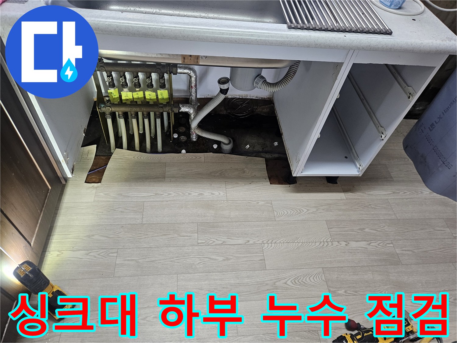 싱크대 밑 공간에 드러난 난방 분배기와 연결된 다양한 배관들
