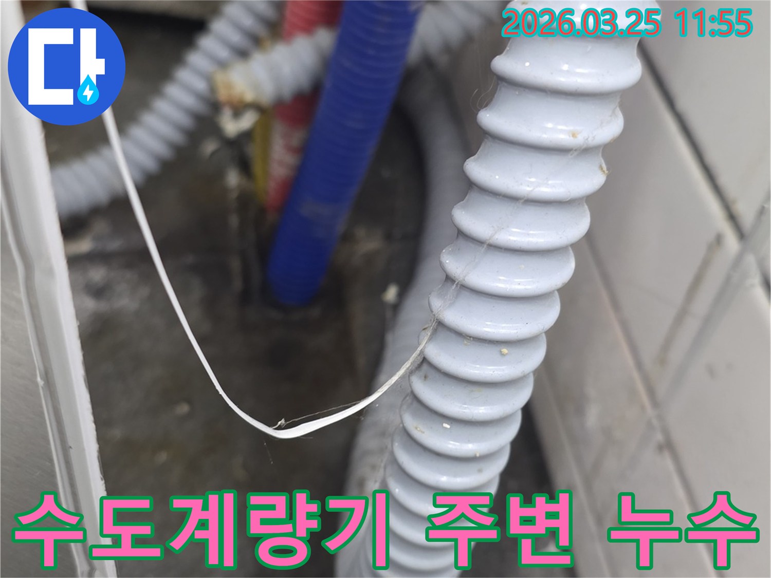 수도 계량기 주변에-설치된 배관과 호스에서-물기나 습기가 감지되어-누수 가능성을 시사하는 모습