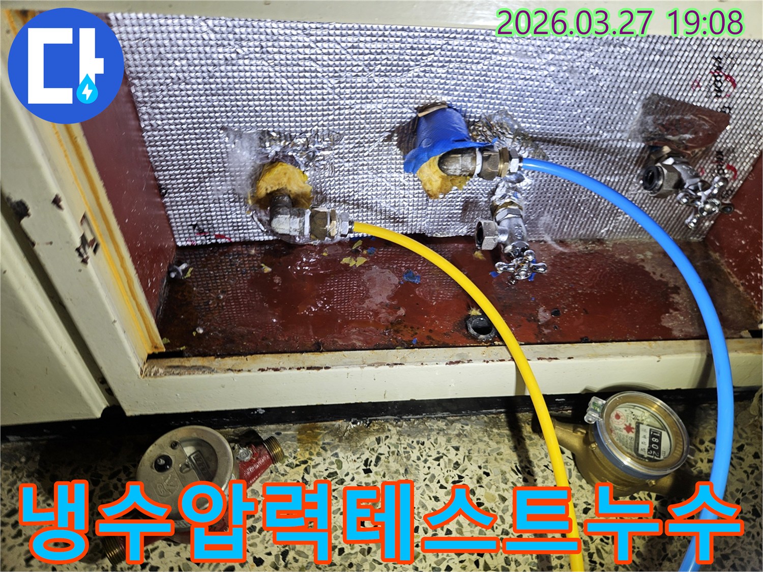 냉수 배관 연결부에서-압력 테스트 중 미세 누수가 발견된-현장을 보여주는 사진입니다-호스가 연결된 배관과 물기가 보입니다
