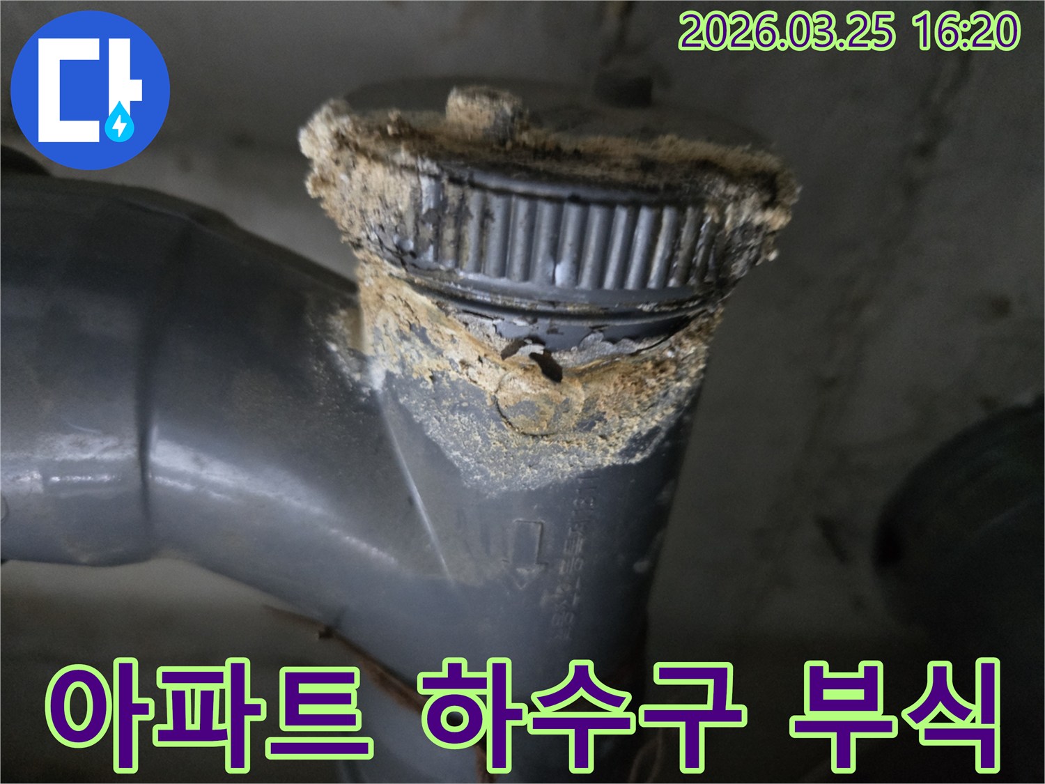 이 이미지는 심하게 부식된 하수구 배관 연결부에서 발생한 누수 흔적을-선명하게 보여주고 있습니다