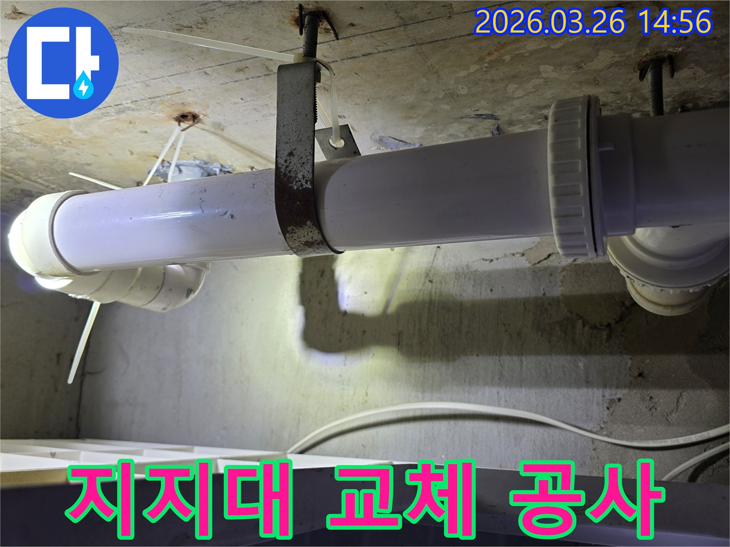 콘크리트 천장에 고정된-오래된 하얀색 하수관과-심하게 녹슨 금속 지지대의 모습