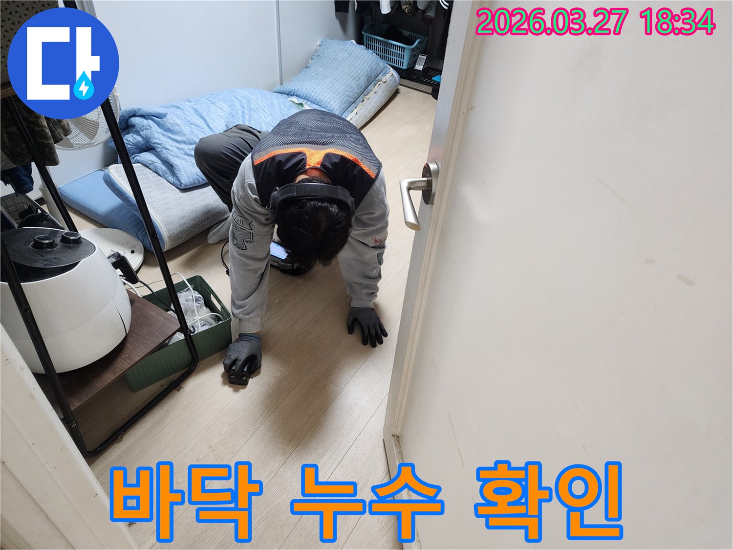 주택 내부에서 발생한-미세한 누수를 파악하기 위해-특수 장비를 착용하고-바닥면을 집중적으로 점검하는 장면입니다.