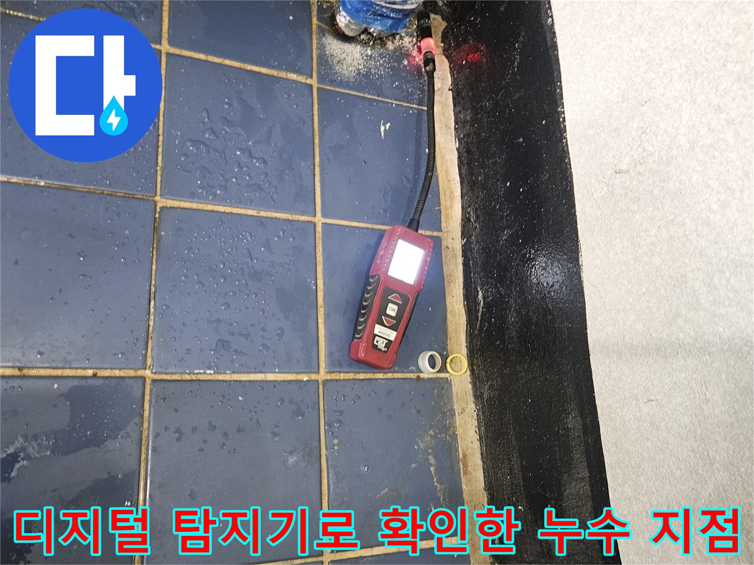 디지털-누수-탐지기를-이용하여-타일-아래-배관의-물샘-위치를-정밀하게-찾는-모습