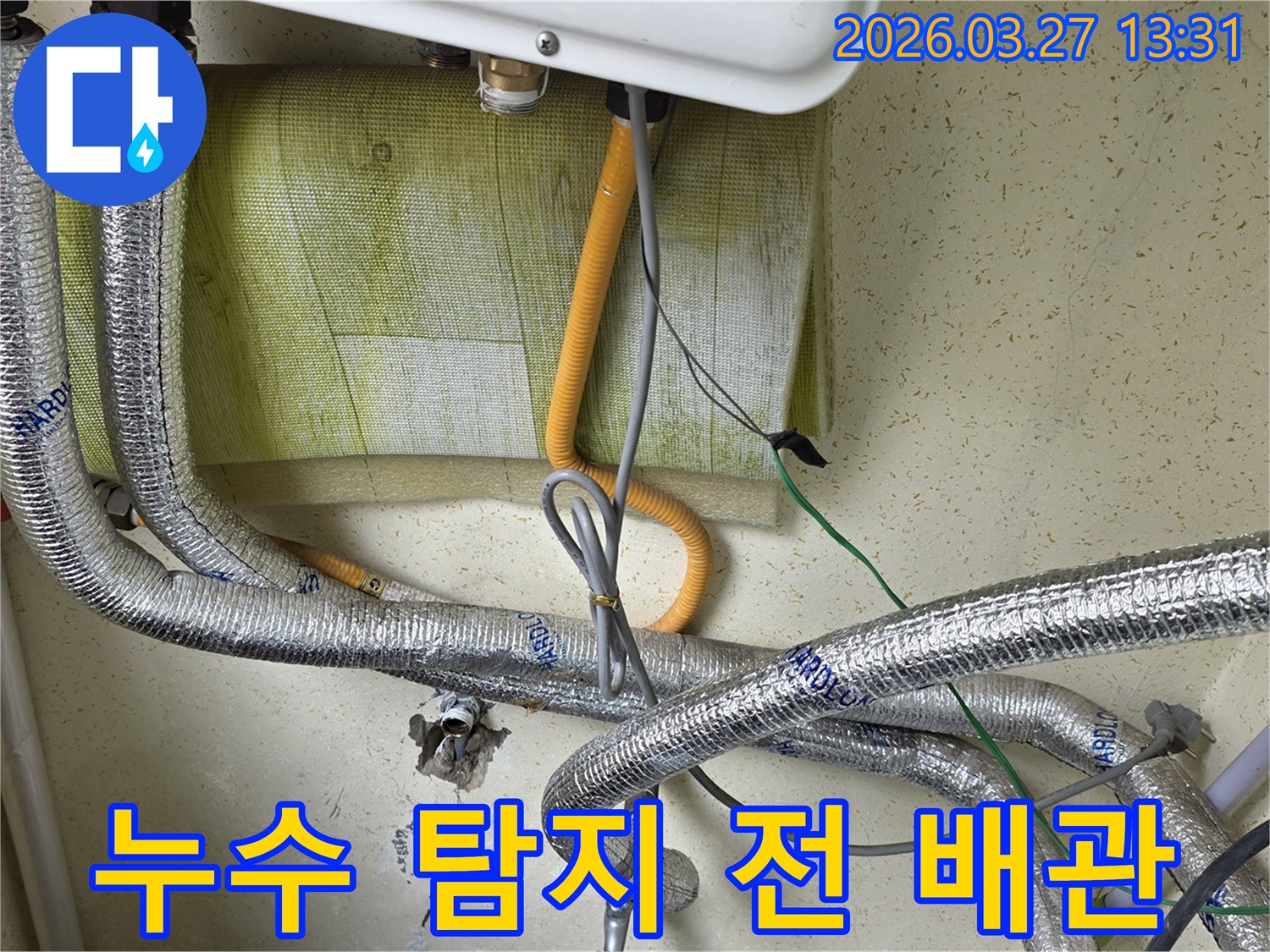 보일러-아래쪽의-복잡한-배관과-전선이-얽혀있는-모습을-보여주며-누수-탐지를-위한-초기-점검-단계입니다.