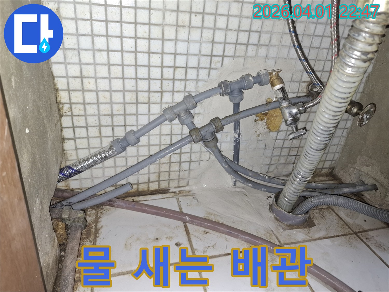복잡한 배관 연결부에서-물이 새어 나와-바닥에 고여있는-누수 상황을-생생하게 보여주는-사진입니다.