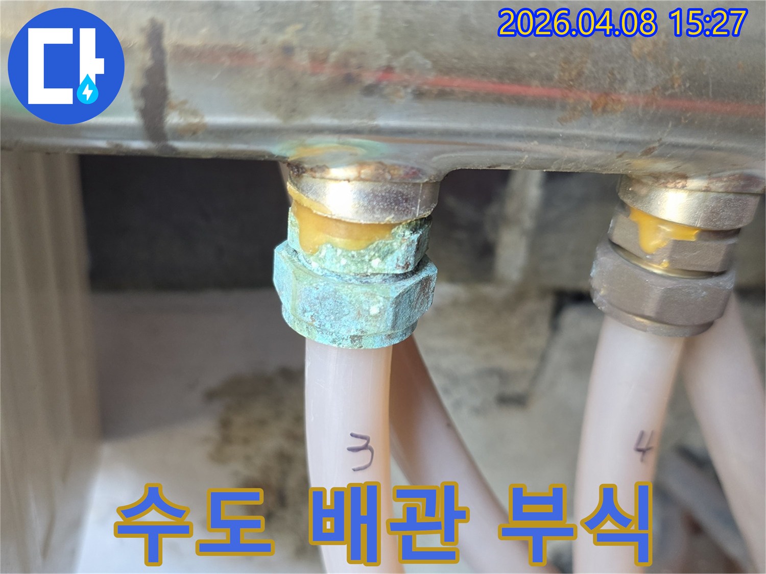 오래된 주택의 수도 배관 연결부에서 발생한-심각한 녹색 부식과 물샘 흔적을 보여주는 사진