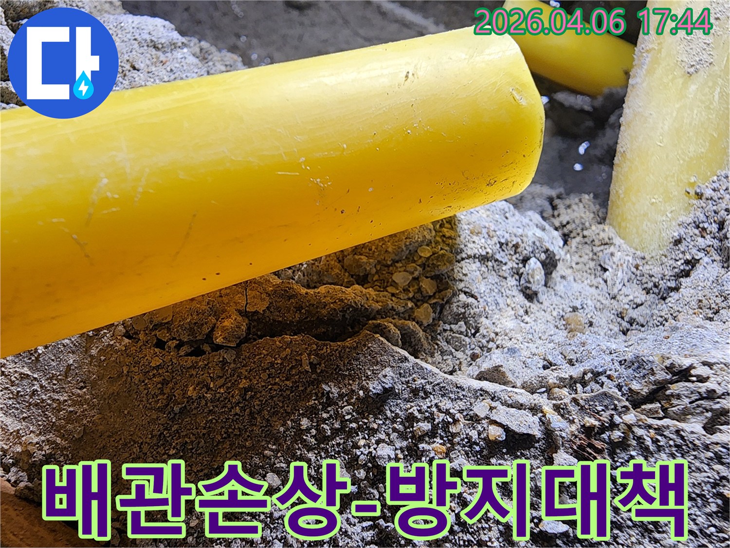 누수 공사 현장에서-땅을 파던 중-드러난 노란색 배관을-안전하게 보호하며-작업하는 모습입니다