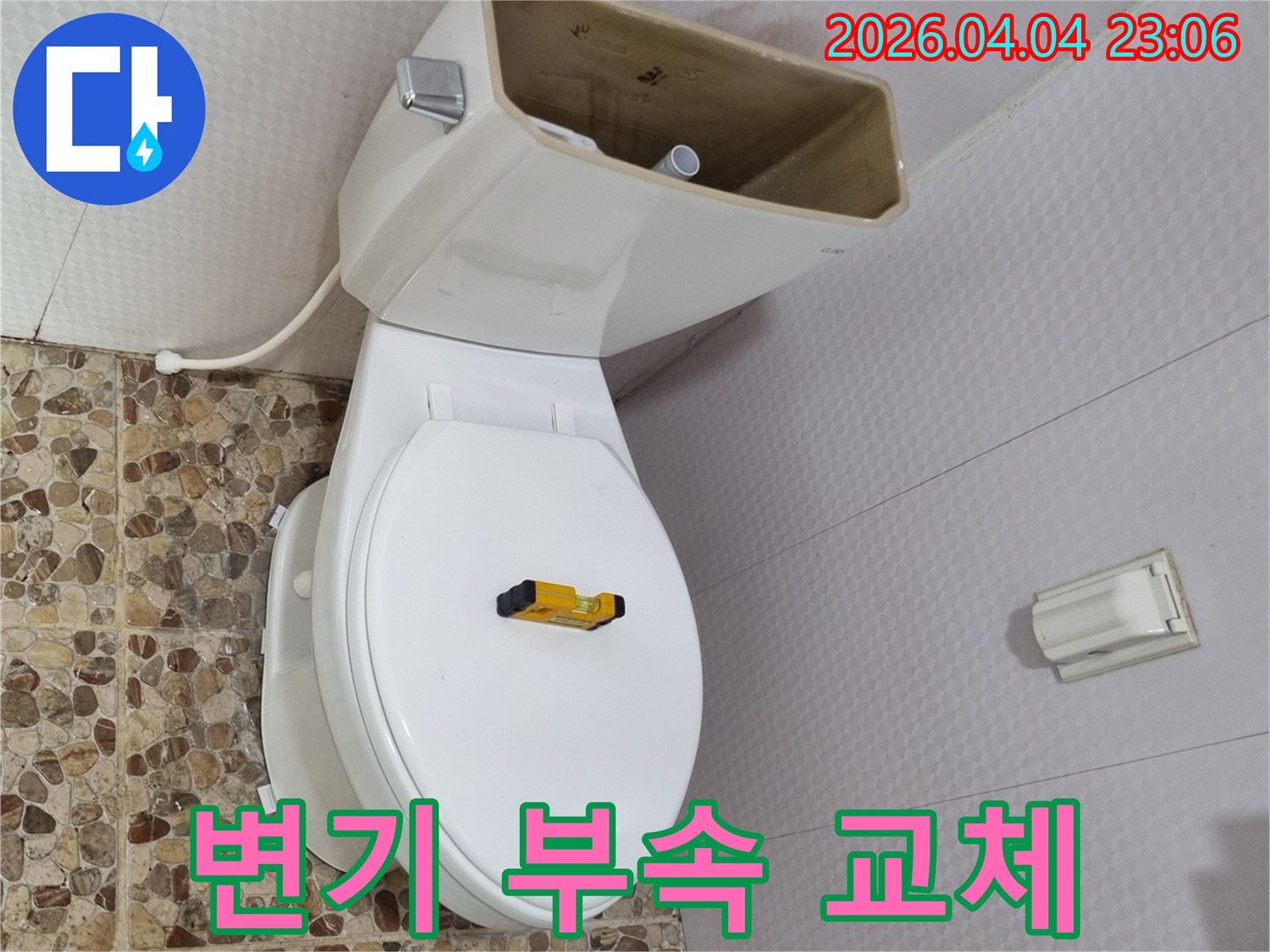 변기 물탱크가 열려 내부 부품이 노출된 상태로-수평계가 변기 시트 위에 놓여-부속 교체를 위한 준비가 완료되었습니다