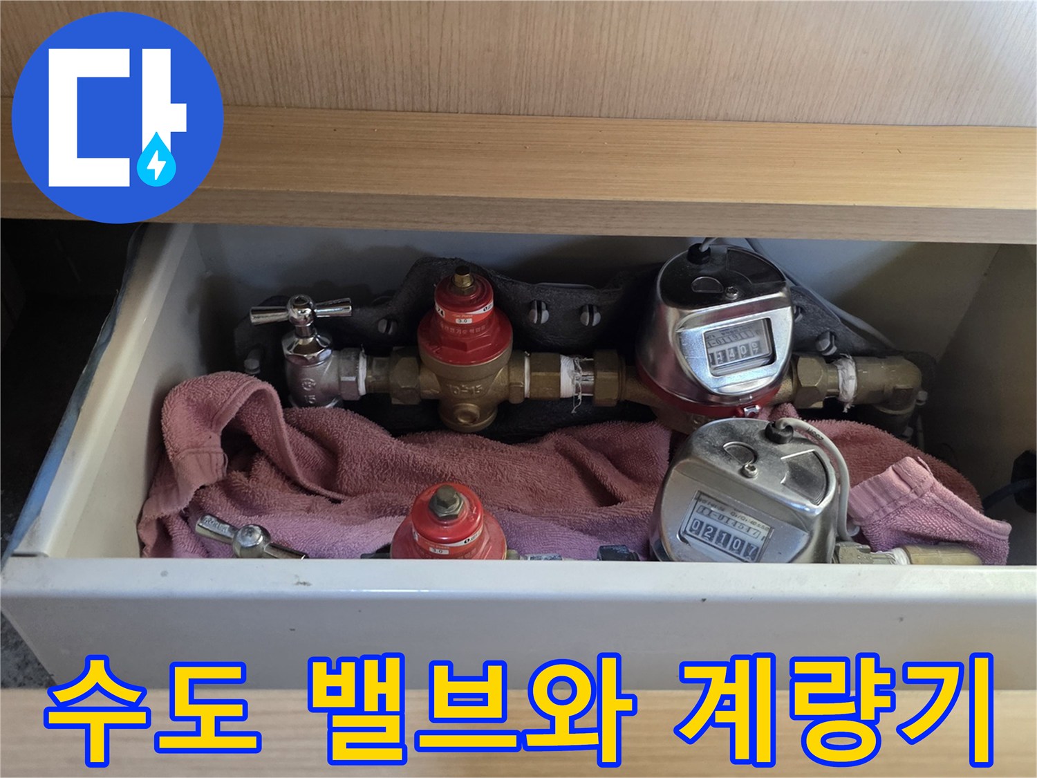 싱크대 하부장 내 설치된 수도 계량기와 배관 사진