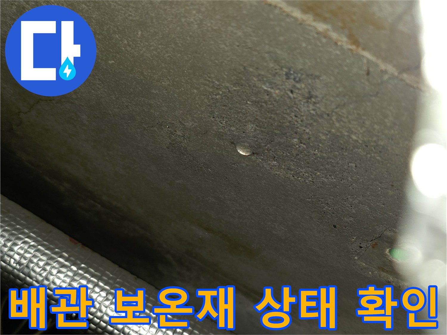 은박 보온재로 감싸진 배관의 표면과 주변 벽체 상태를 근접 촬영한 사진입니다.