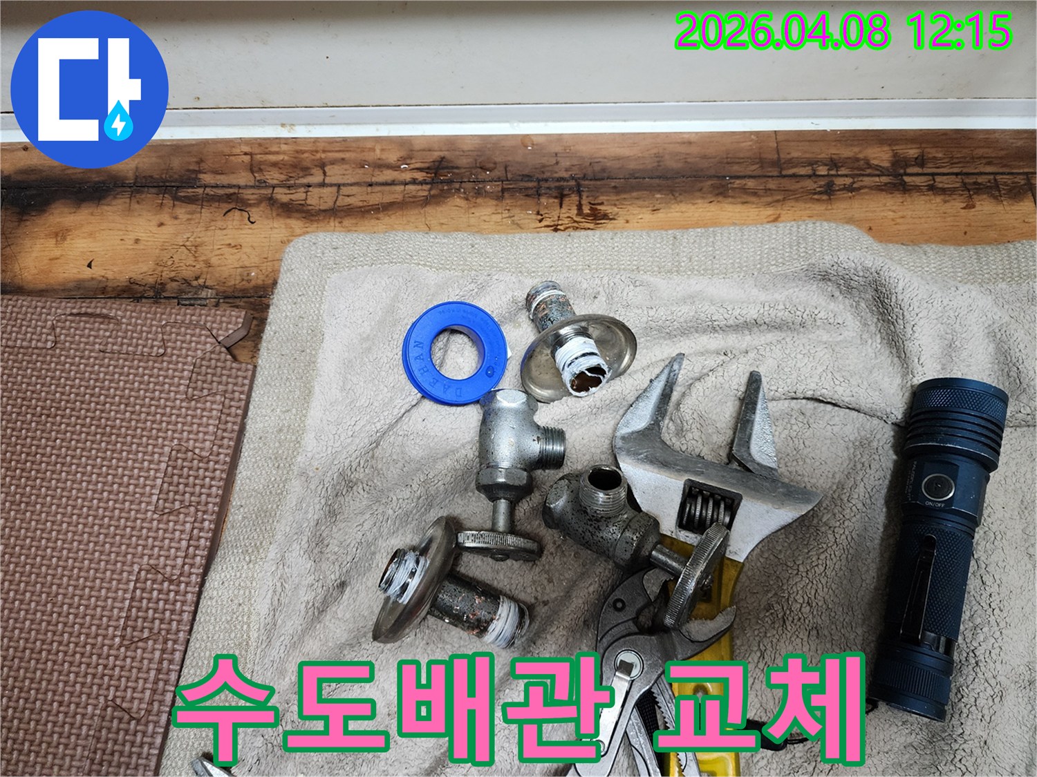 수도 배관 교체 작업을 위해-준비된 새 부품들과-다양한 전문 공구들이-수건 위에 깔끔하게 놓여있습니다