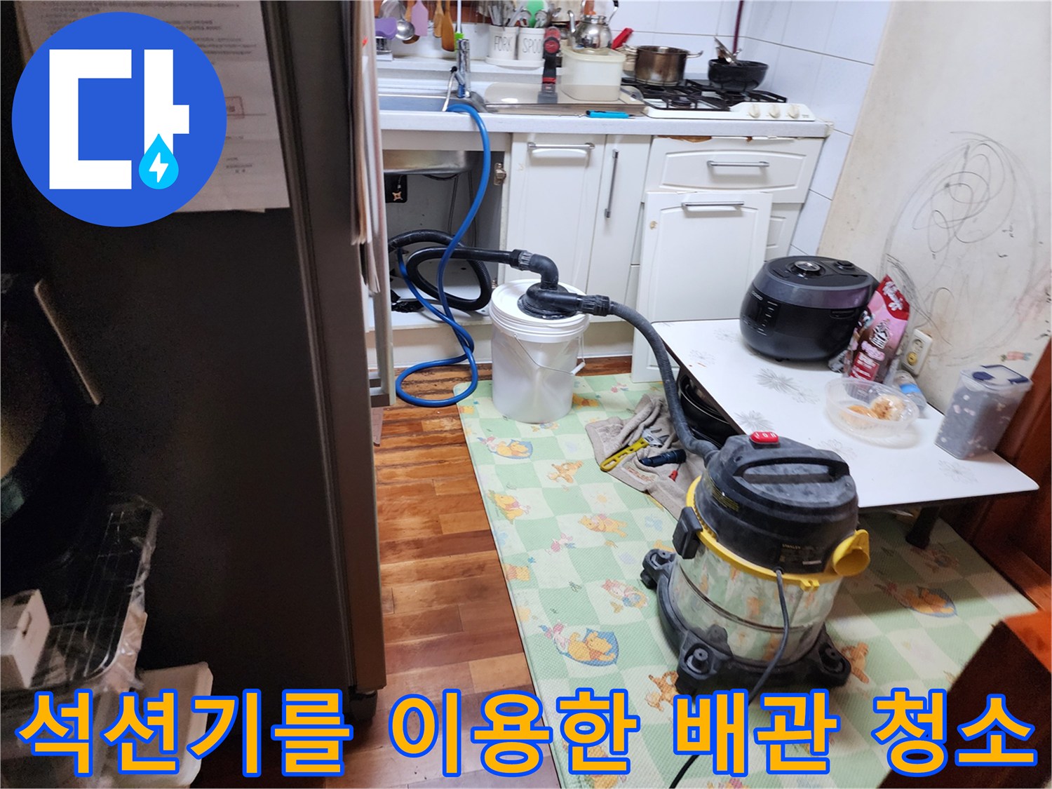 싱크대 하단부 배관 오염 제거를 위해 석션 호스를 연결하여 작업 중인 장면
