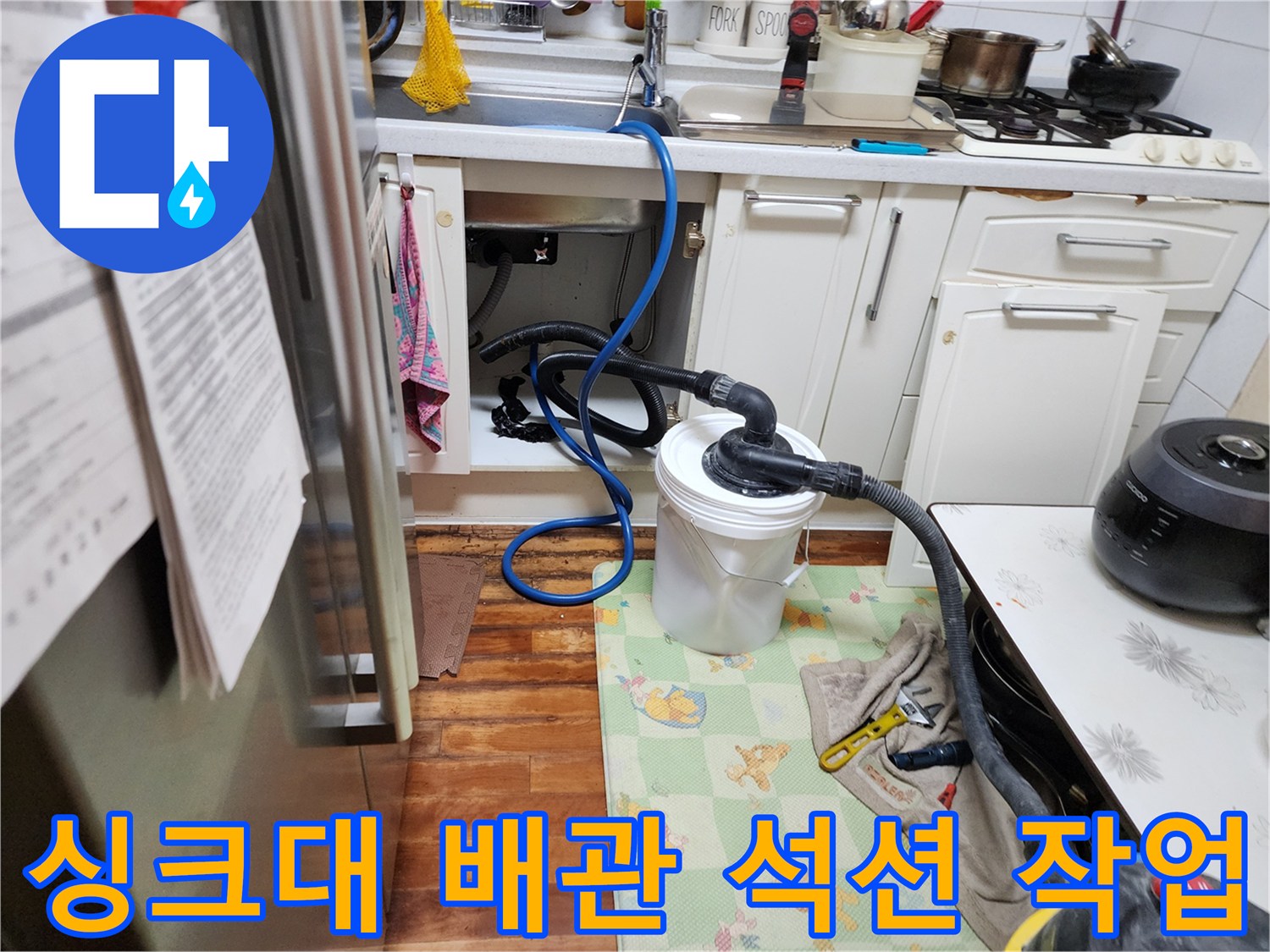 주방 싱크대 하부장 배관에 연결된 석션 장비와 오물 수거통 모습