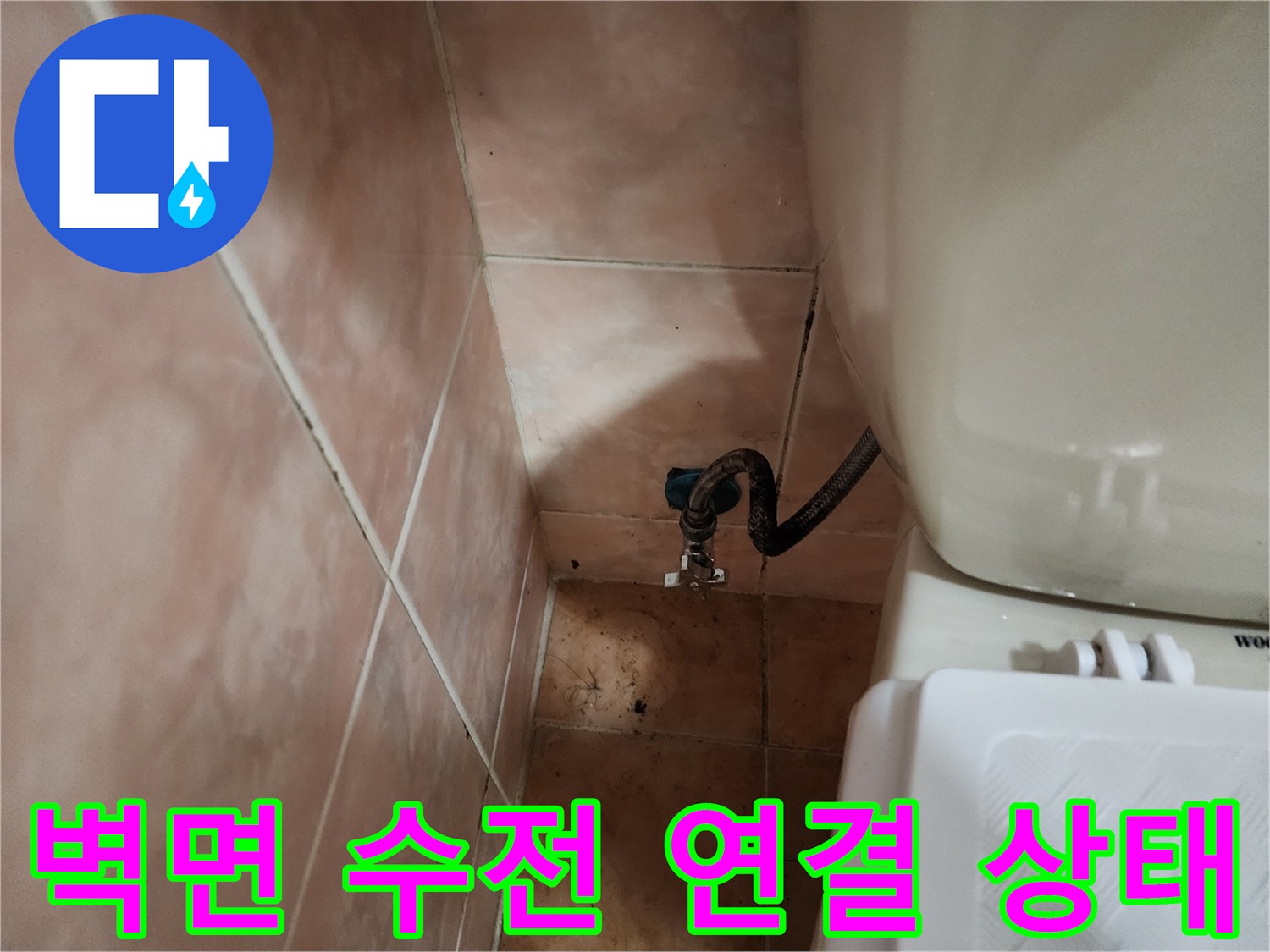 타일 벽면에 설치된 세탁실용 수도꼭지와 배관 호스 모습입니다.