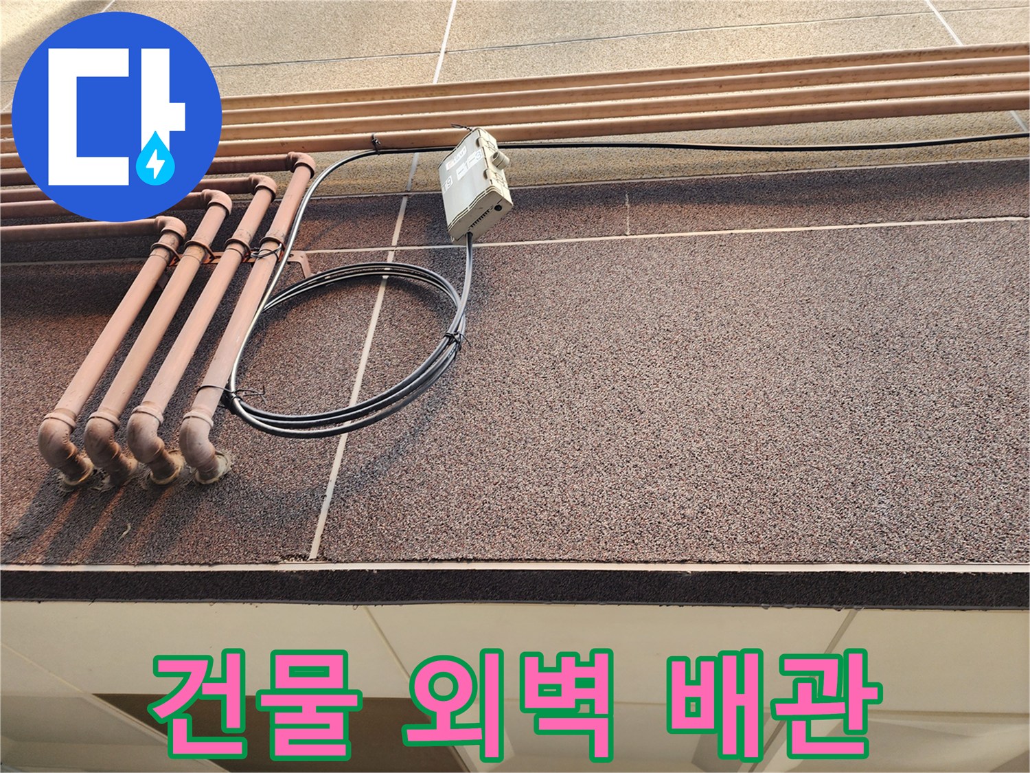 건물 외벽에 설치된 갈색 배관과 전선 연결 부위 모습
