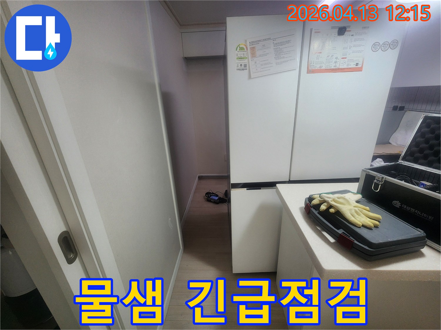주방 냉장고 주변에서 발생한-물샘 현상을 긴급 점검하기 위해-탐지 장비를 준비하는 현장