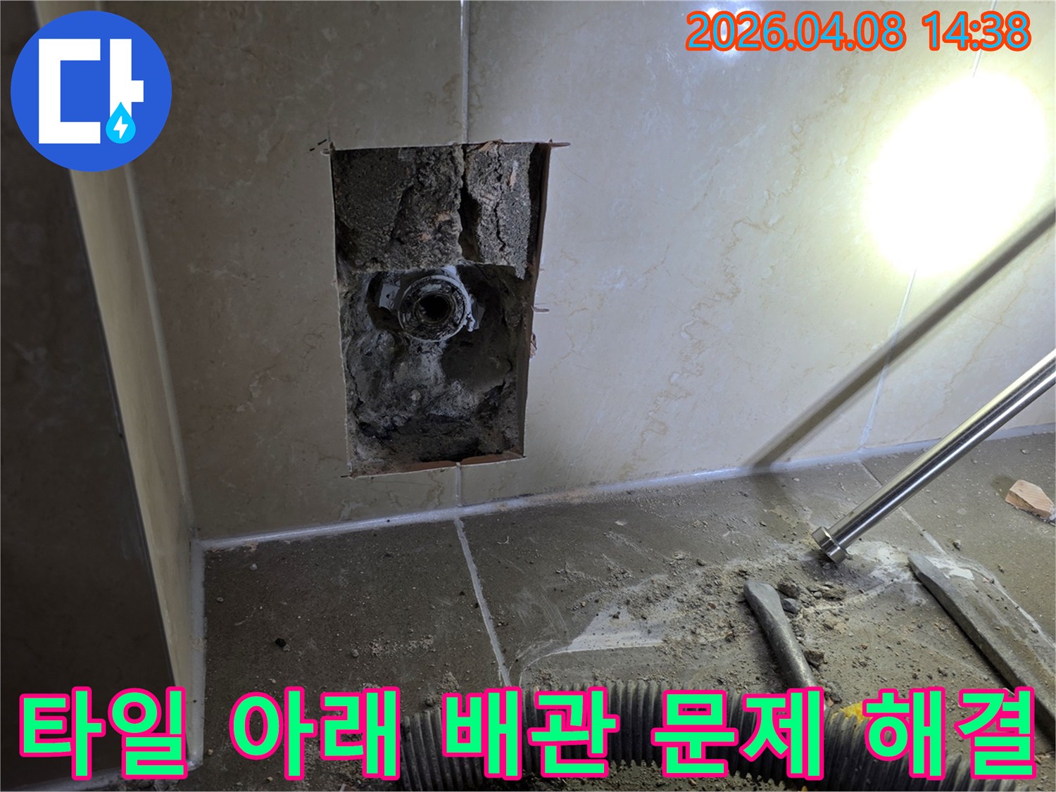 김포시의 한 아파트에서 타일 아래 숨겨진 배관 문제를 해결하기 위해 벽면을 개방한 현장입니다-노출된 배관의 손상 여부를 확인 중입니다