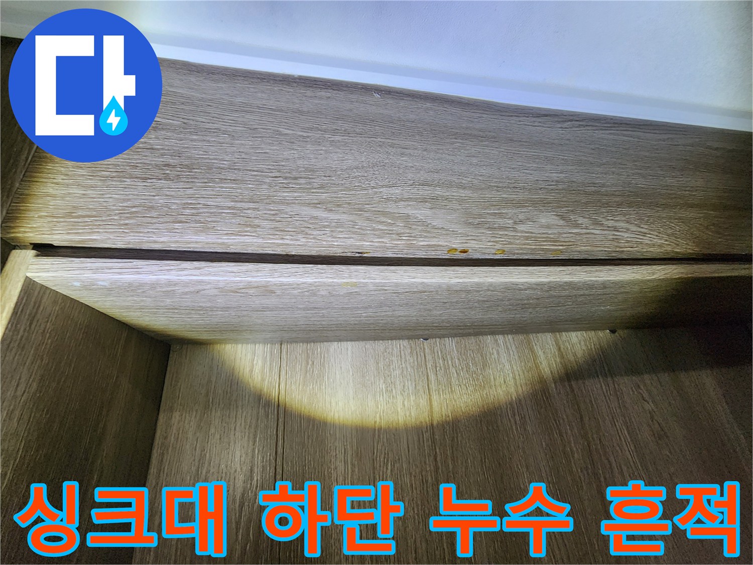 주방 싱크대 걸레받이 안쪽-나무 마감재에 나타난 젖은 얼룩과 습기 상태
