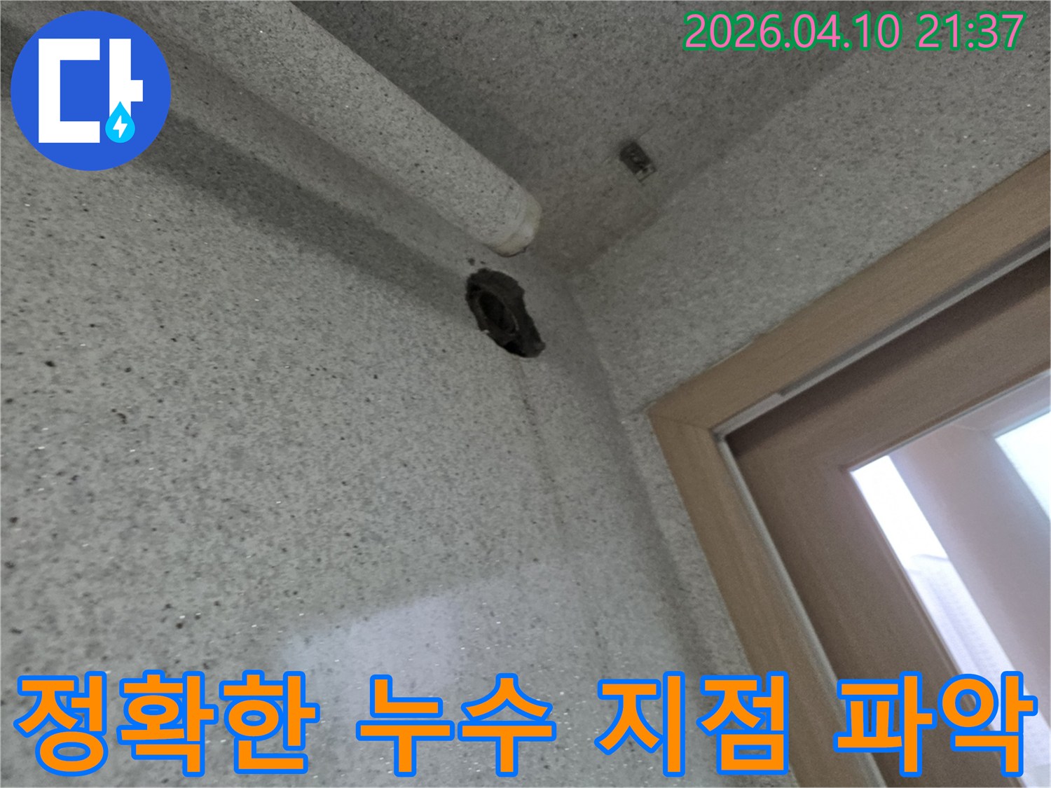 벽면의 구멍과-그 아래로 흐른 물자국을 통해-누수 지점을 시각적으로 보여주는 사진입니다
