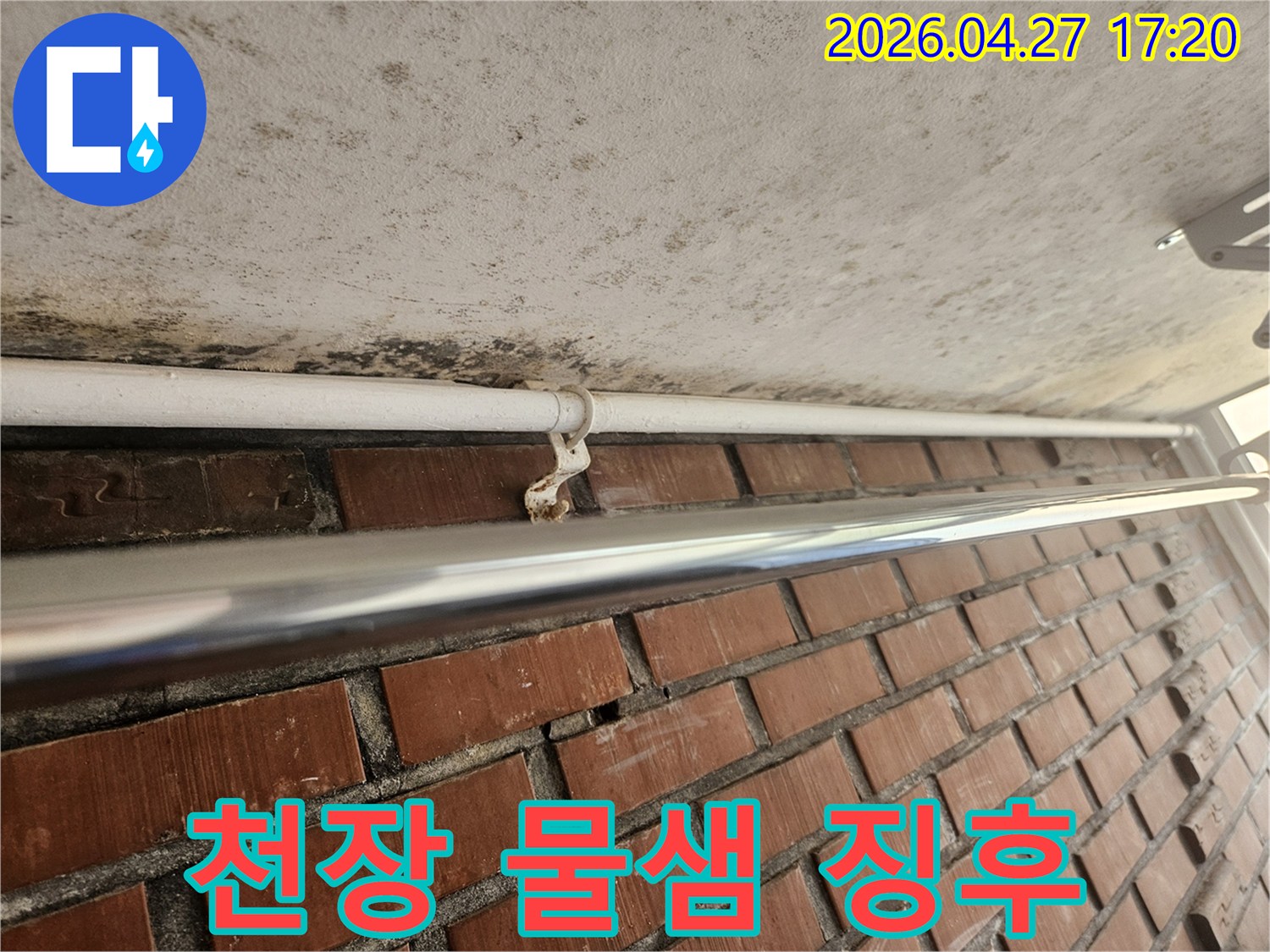 천장 표면에 나타난 물샘의 징후와-배관 지지대의 녹슨 모습이-누수 문제를 명확히 보여줍니다