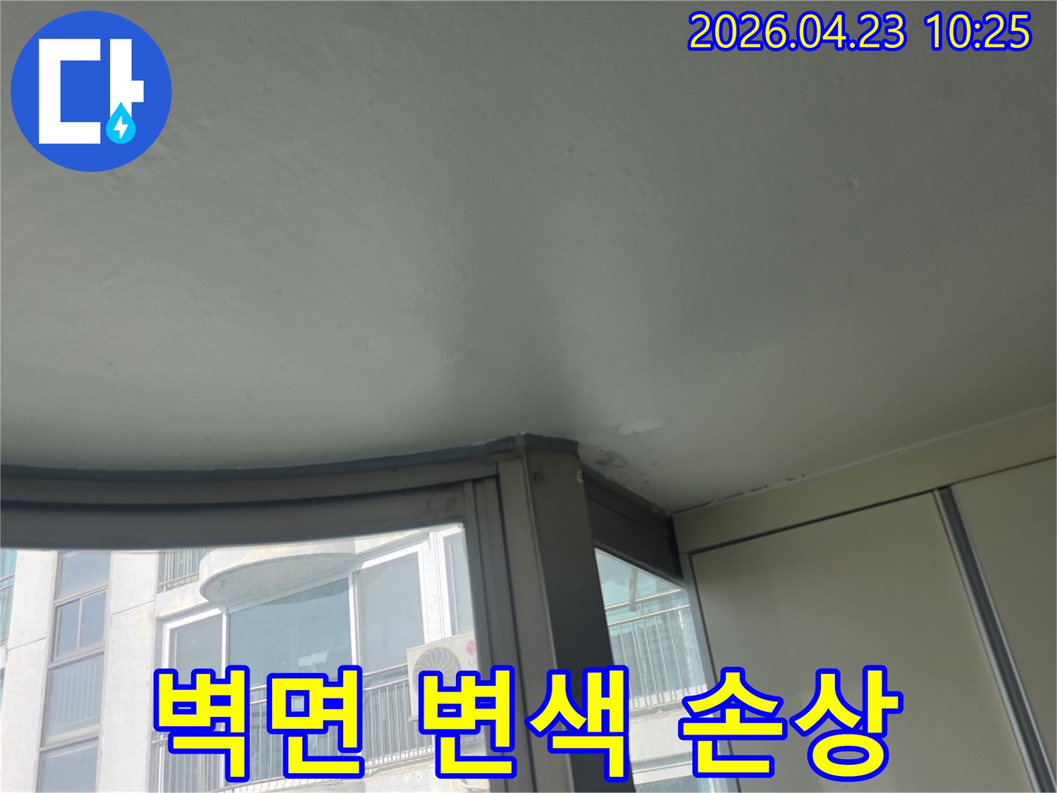이 이미지는 아파트 창가 천장과 벽면이 누수로 인해 변색되고 손상된 모습을 보여줍니다-물이 스며들어 마감재가 약해진 상태입니다