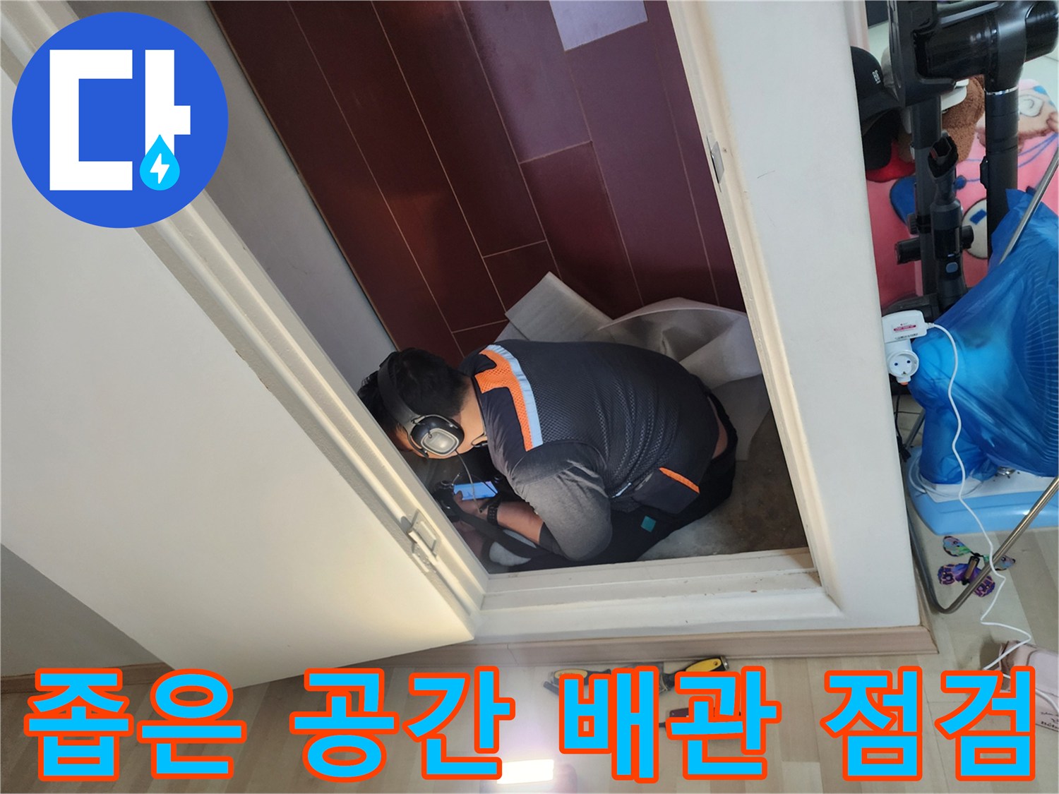 좁은 화장실 입구에서 배관 상태를 면밀히 조사하고 있는 모습입니다.