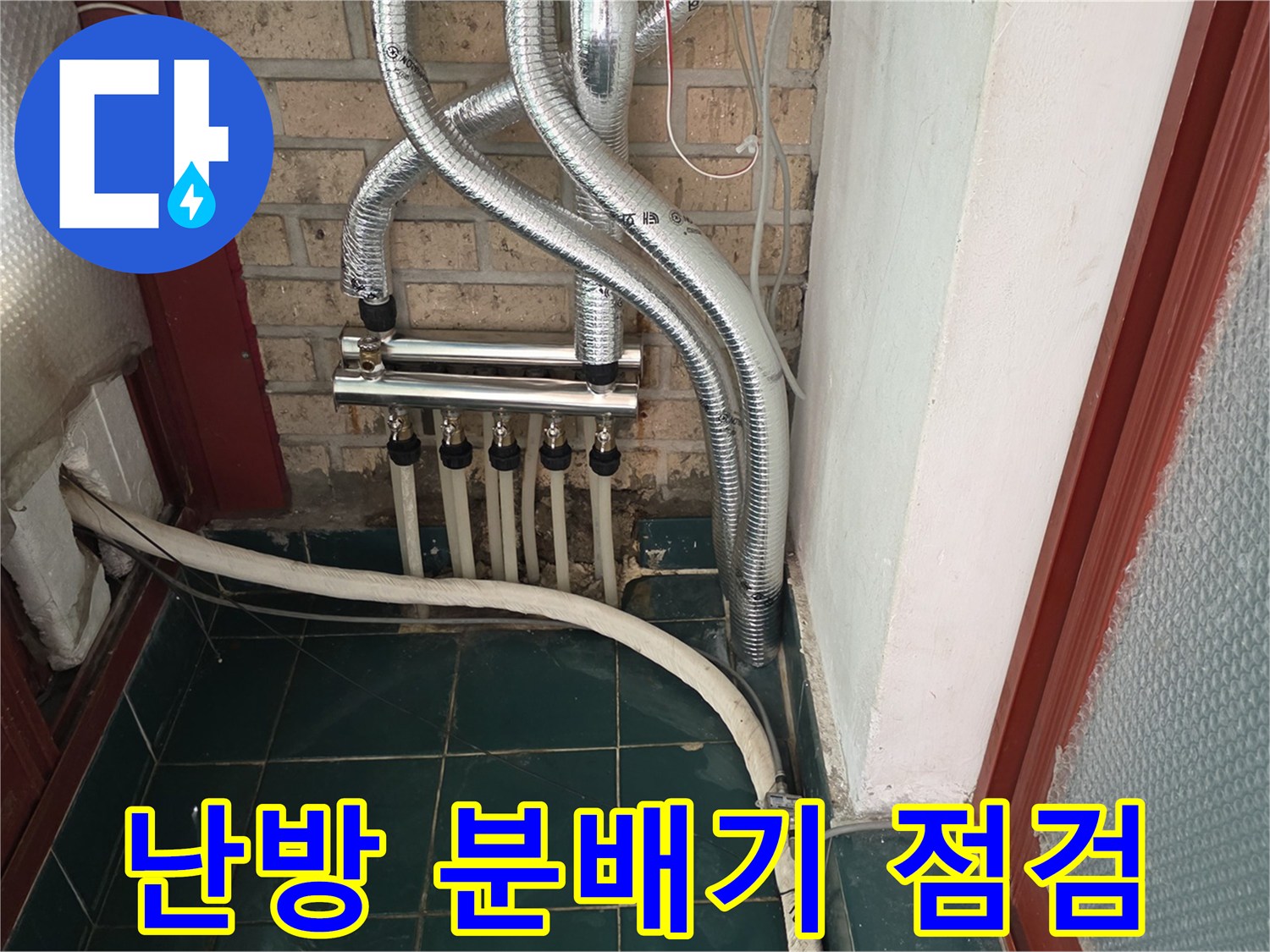 은색 보온재로 감싸진 배관과 하단에 위치한 난방 분배기 사진입니다.