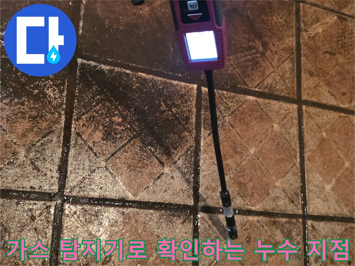 공장 내부 타일 바닥 위에서 가스 탐지기를 사용하여 배관의 물샘 지점을 정밀하게 추적하고 있습니다.