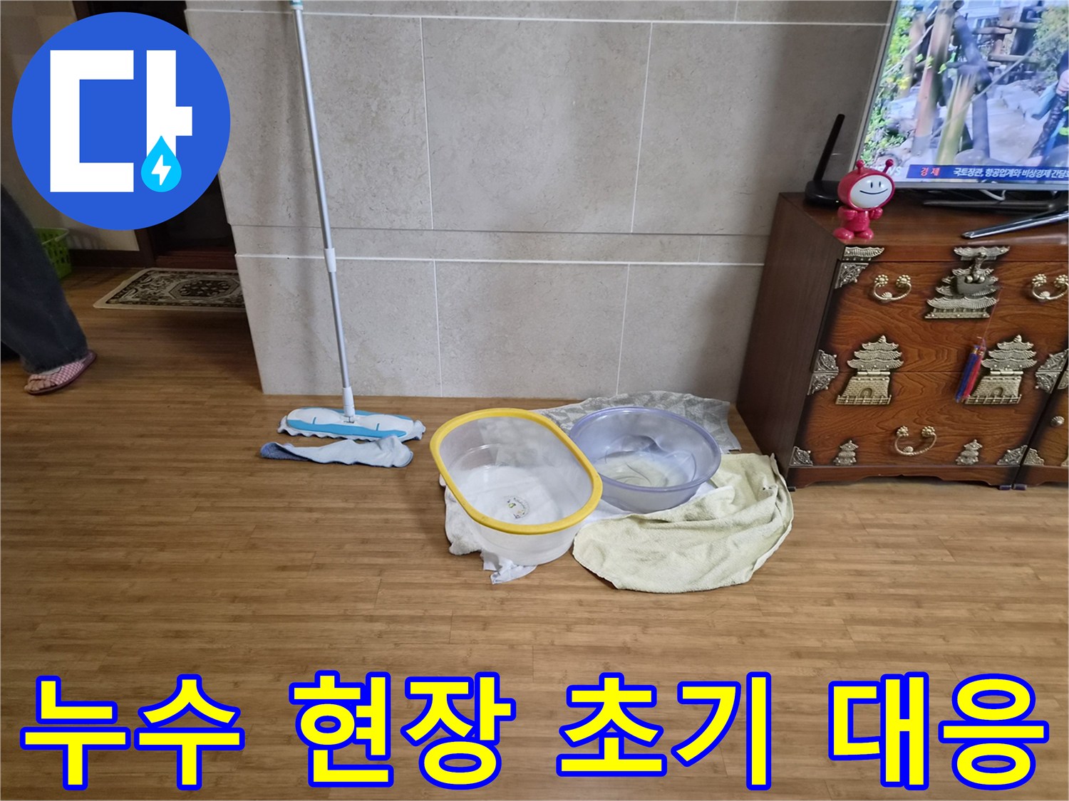 누수로 인해 바닥에 물이 고이는 것을 방지하기 위해 물받이와 걸레를 배치한 모습-주택 내부의 물샘 현상에 대한 신속한 조치