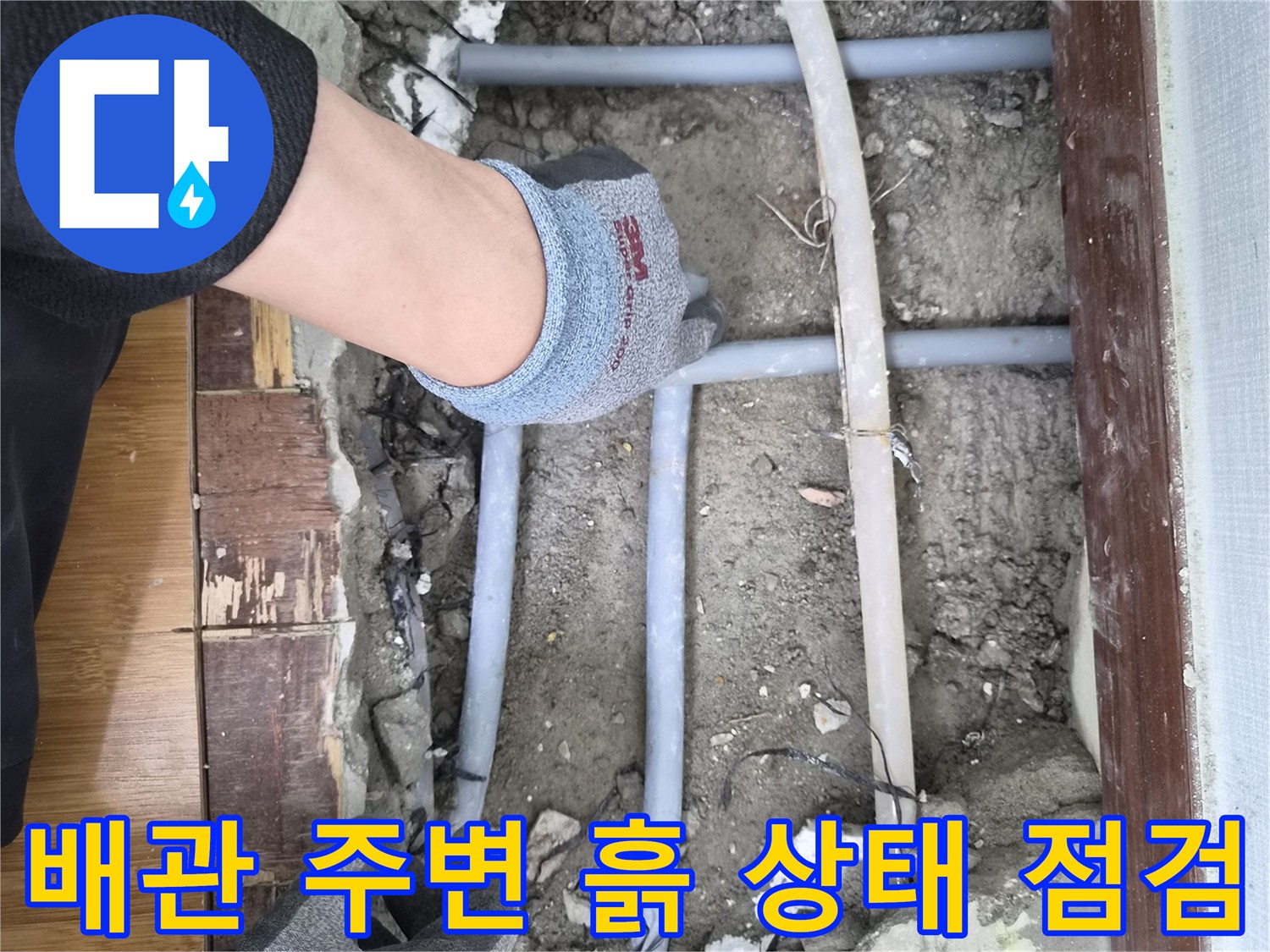 주택 누수 배관 주변의 흙 상태를-점검하고 되메우기 위한-다짐 작업을 준비하는 모습입니다