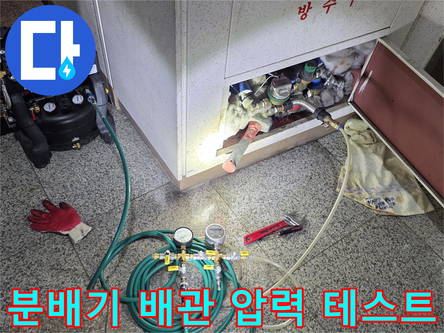 싱크대 하부 분배기에 공압 장비를 연결하여 배관의 기밀 상태를 점검하는 모습입니다.