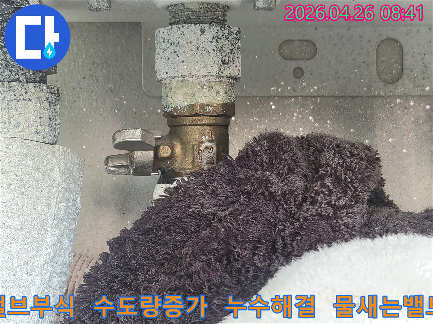 부식으로 인해 하얗게 변색된 수도 밸브에서 물이 새고 있는 현장-아래 수건이 젖어있는 모습-수도 사용량 증가의 원인을 보여주는 이미지