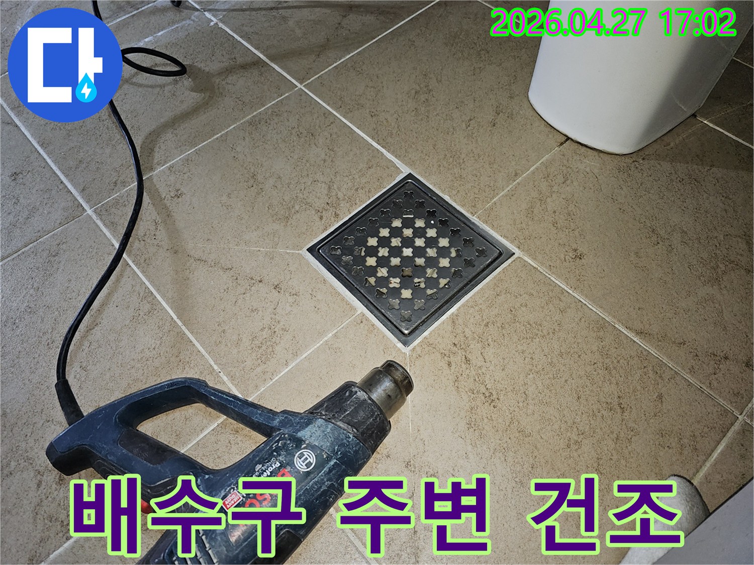 누수 보수 작업 후-전문가가-히팅건으로-욕실 배수구 주변을-건조하며-마무리하는 모습입니다.